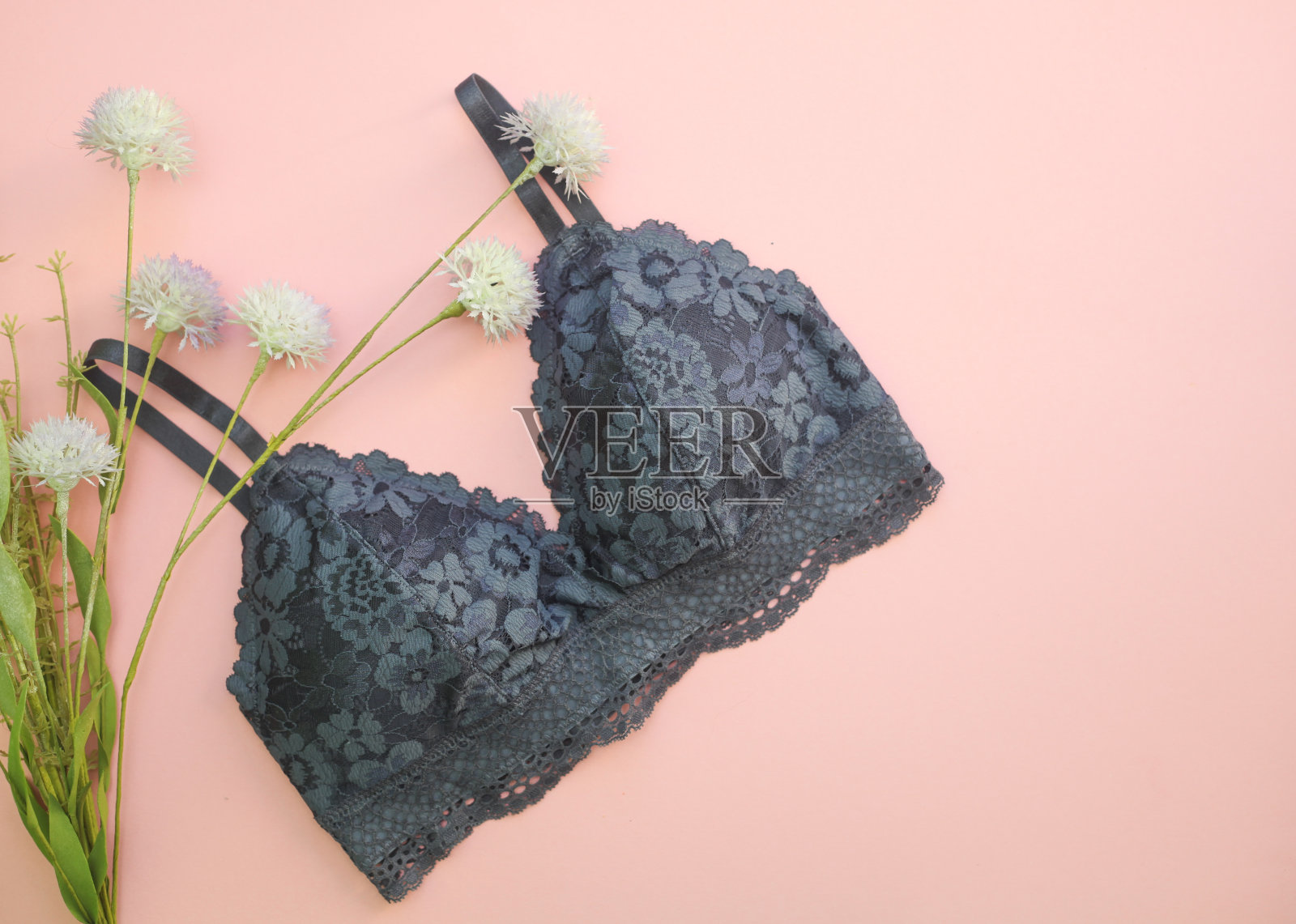 时尚的深蓝色蕾丝内衣和花在粉红色的背景。俯视图，平放照片摄影图片