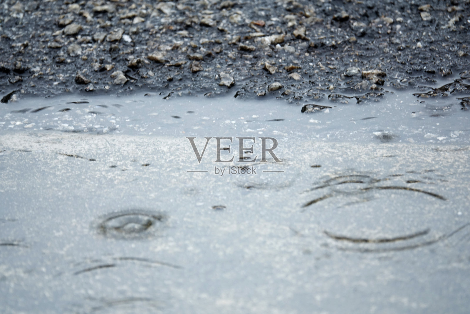 雨在柏油路或柏油路上产生波纹，模糊，高对比度和选择性聚焦图像。照片摄影图片