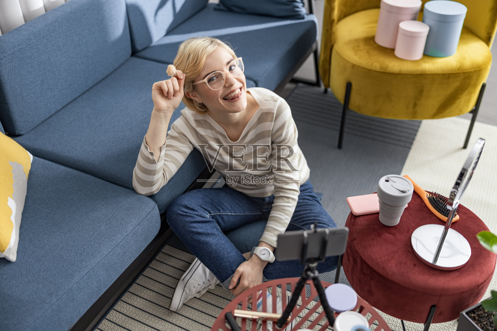 微笑的漂亮女士休息在地板上，同时制作视频照片摄影图片