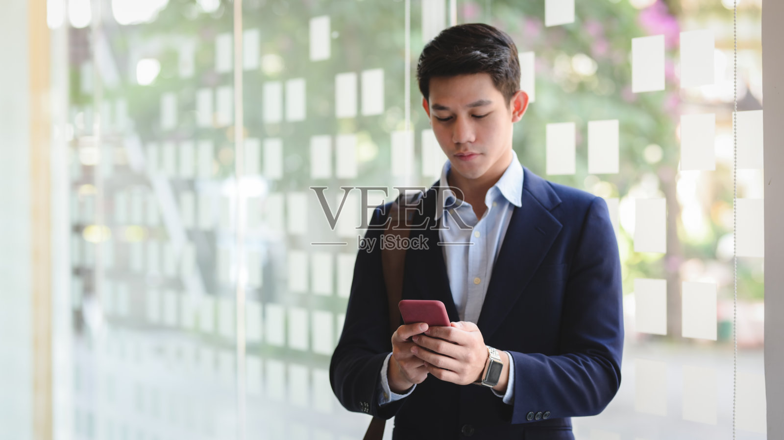 商人站在办公室里用智能手机发短信的镜头照片摄影图片