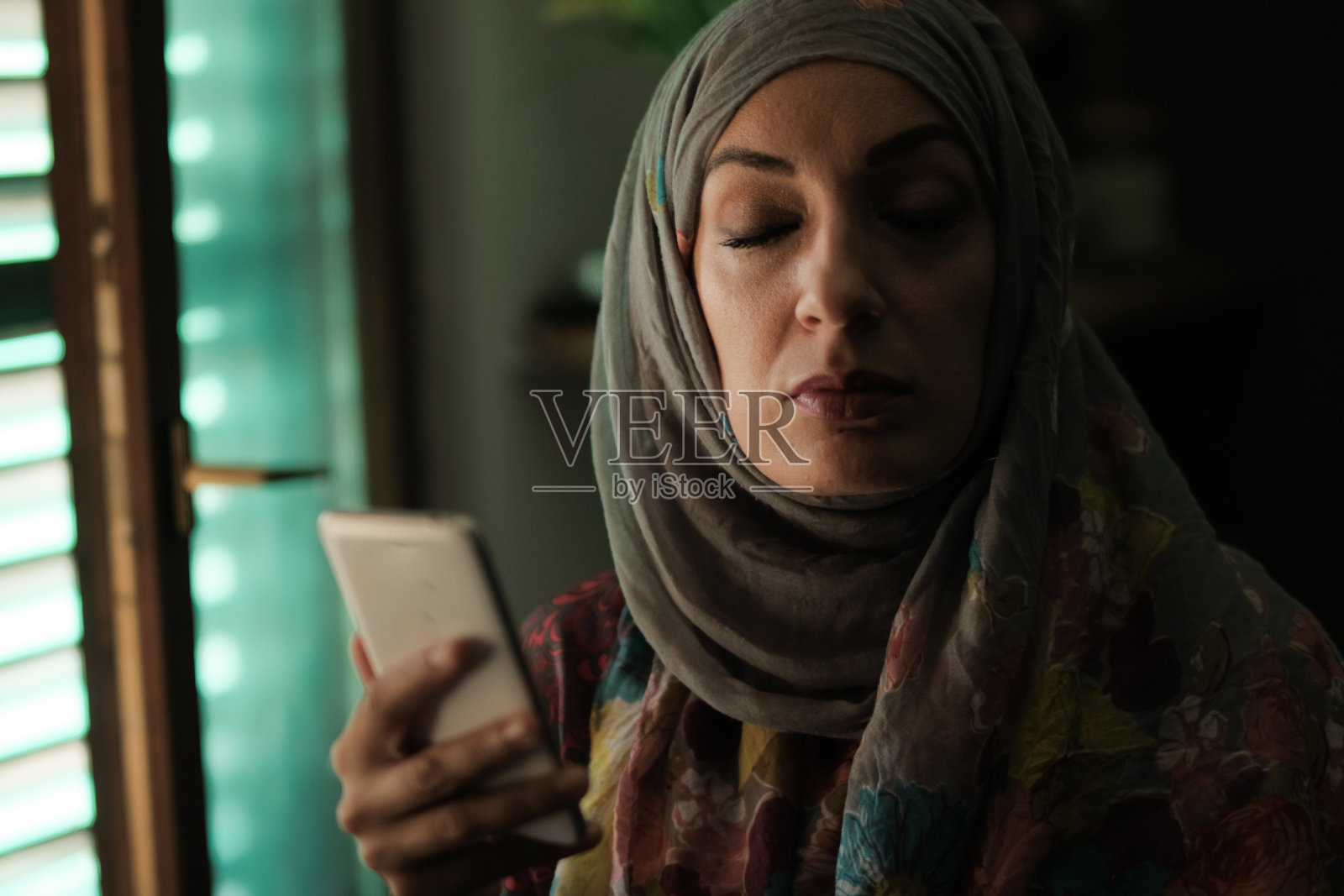 穆斯林女性在黑暗的房间里使用手机照片摄影图片