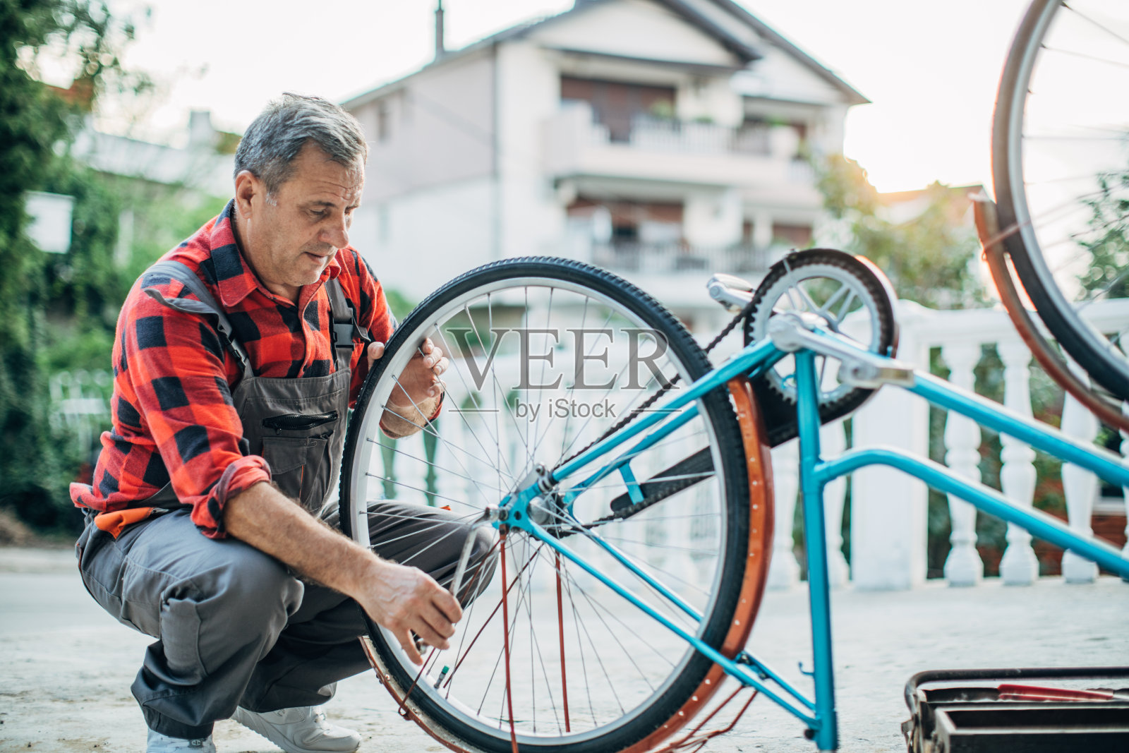 老人独自在前院修自行车照片摄影图片