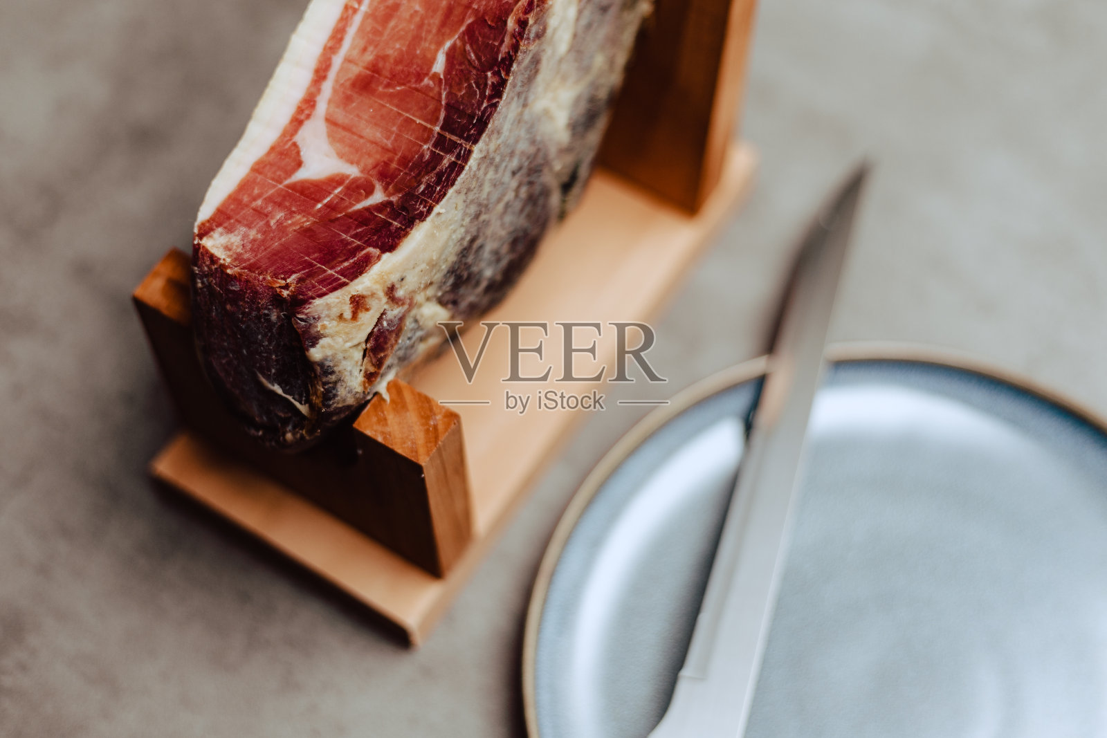 伊比利亚火腿放在火腿架上，配有刀和盘子照片摄影图片