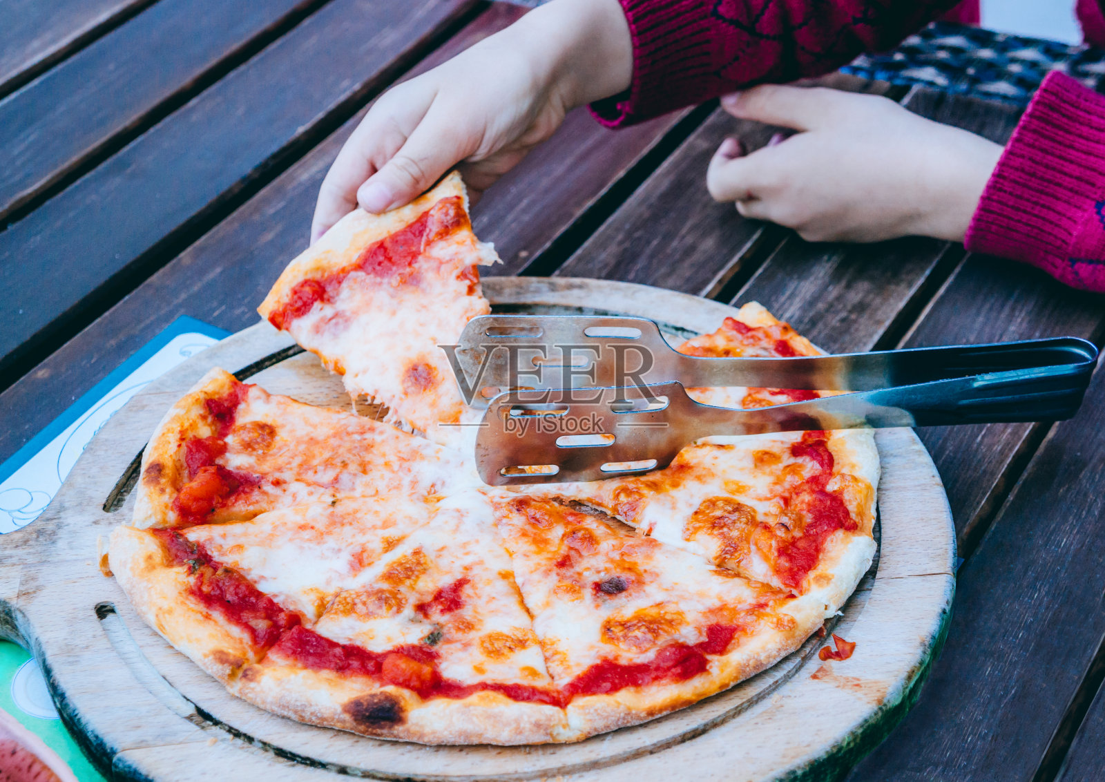 小男孩的手拿着一片玛格丽特披萨照片摄影图片