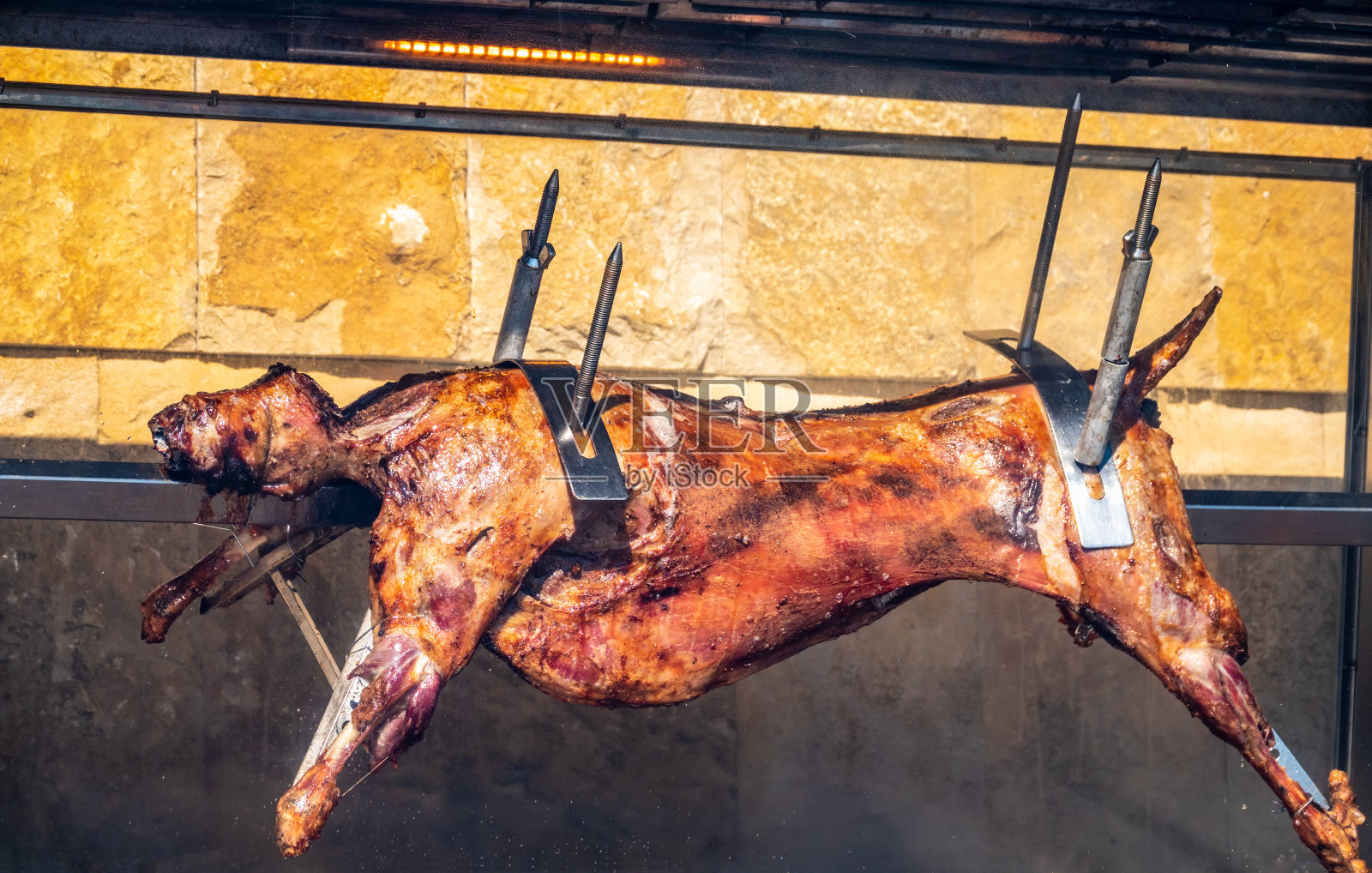 小羊的尸体是用烤肉叉烤的。照片摄影图片