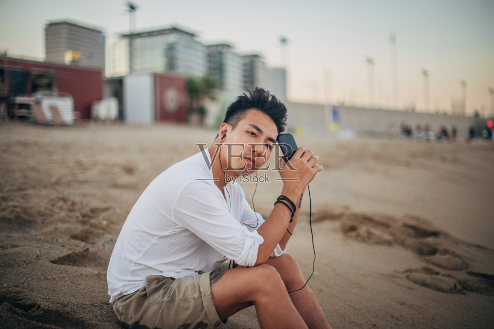 帅哥在沙滩上听音乐照片摄影图片