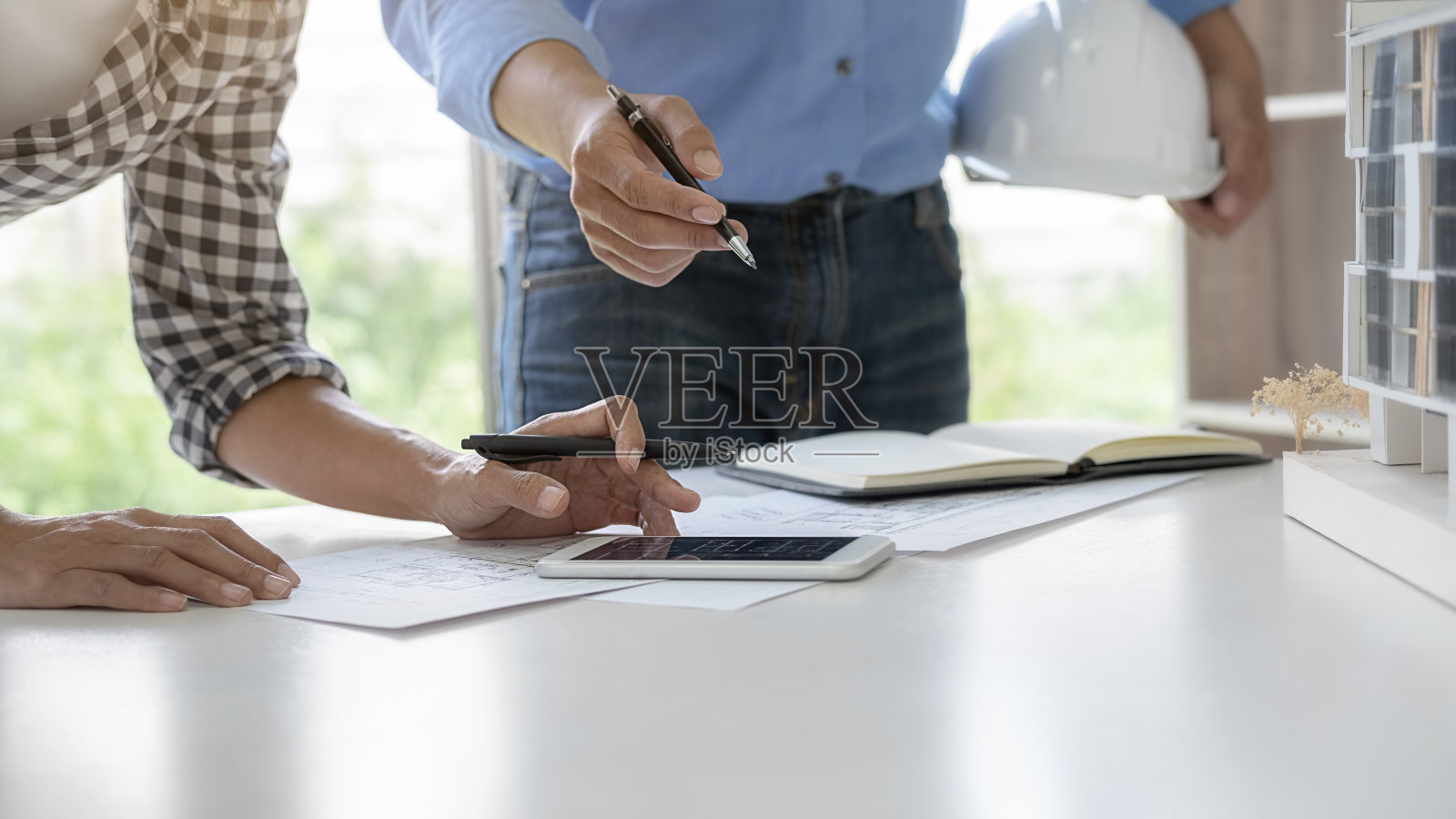 工程师或建筑师团队在办公室使用建筑模型和蓝图进行施工项目合作，施工概念照片摄影图片