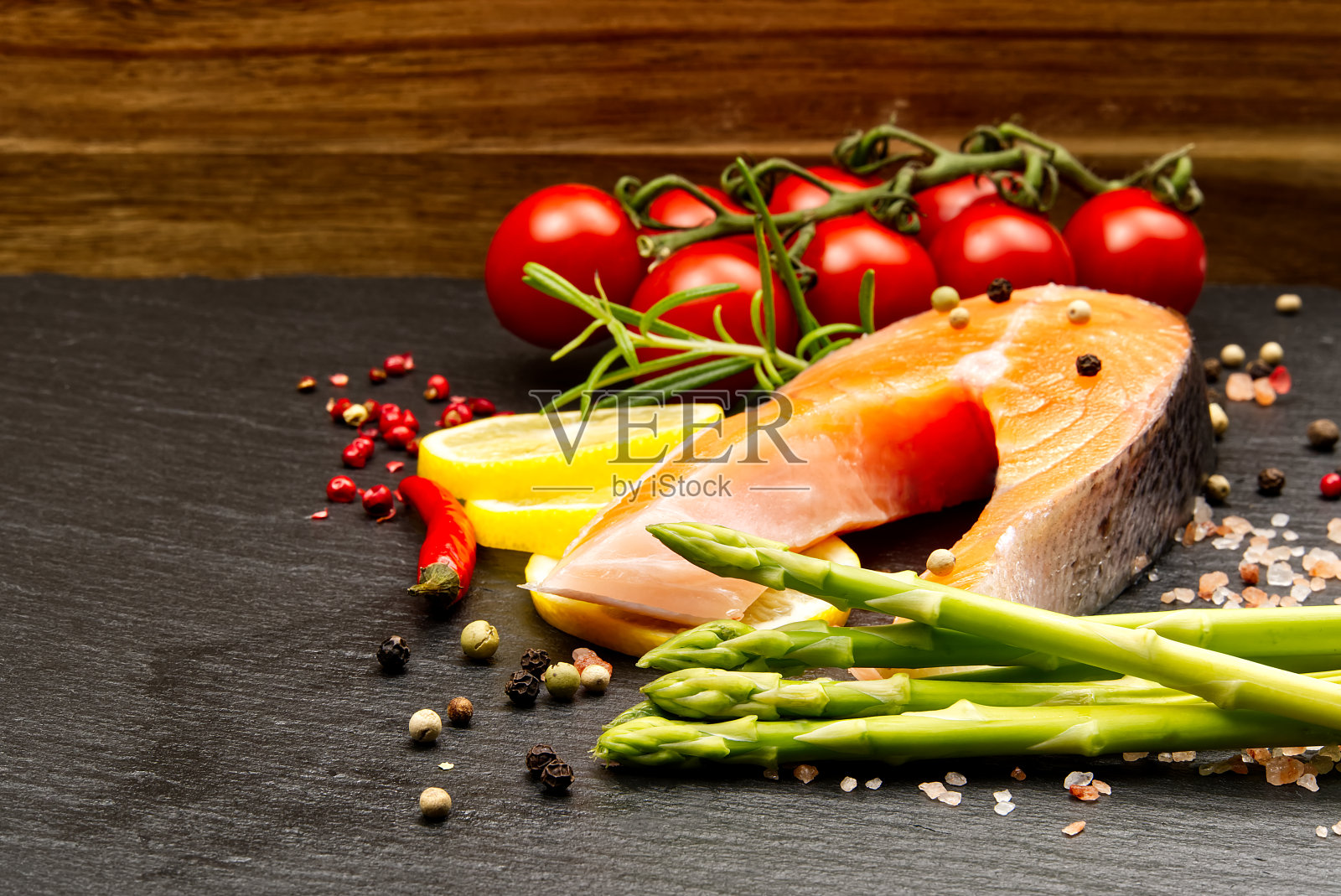 新鲜的生鲑鱼排配胡椒，盐，柠檬和橄榄油在黑色的背景。健康饮食理念。用香料烹饪鱼的准备工作照片摄影图片