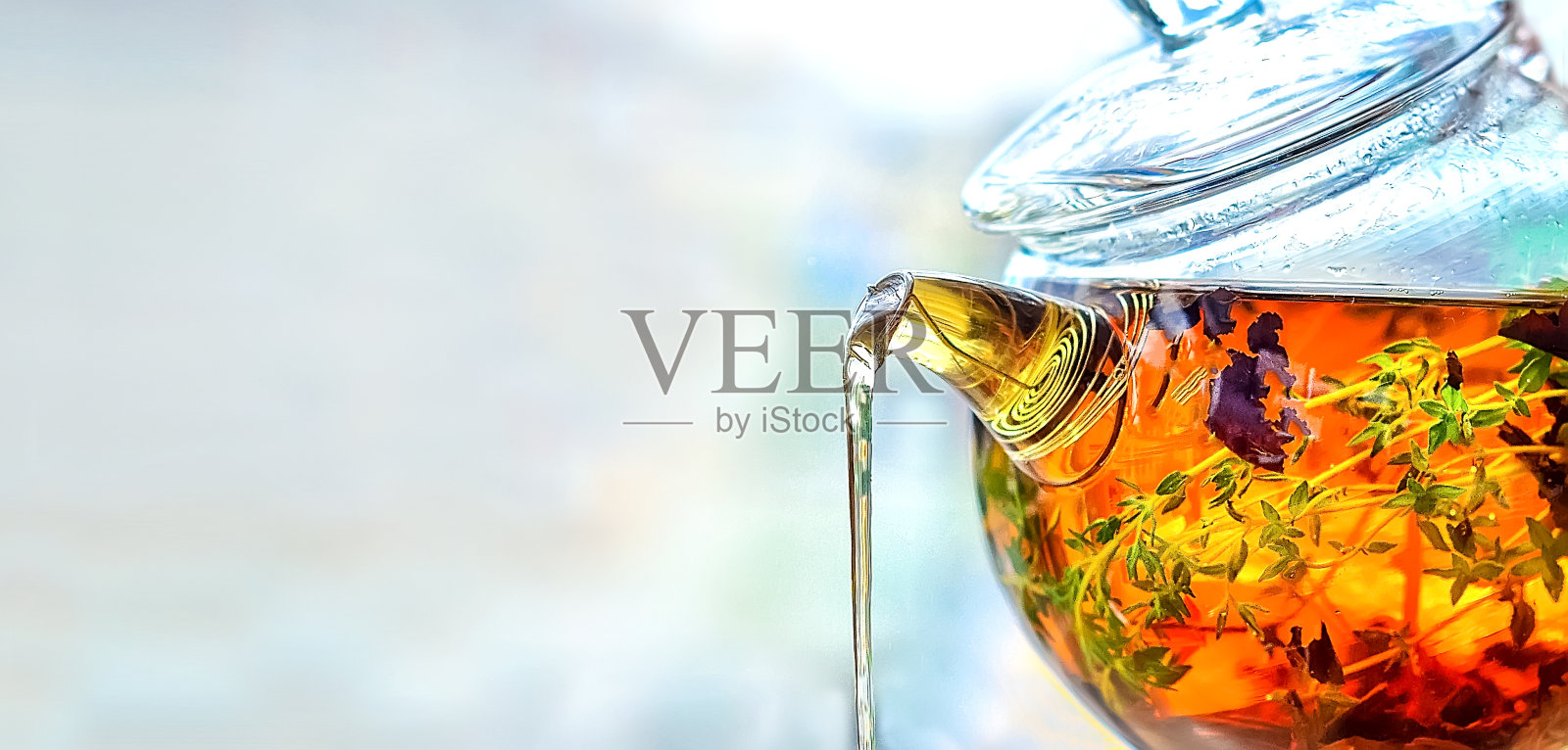 从一个玻璃壶倒茶在一个轻的背景照片摄影图片