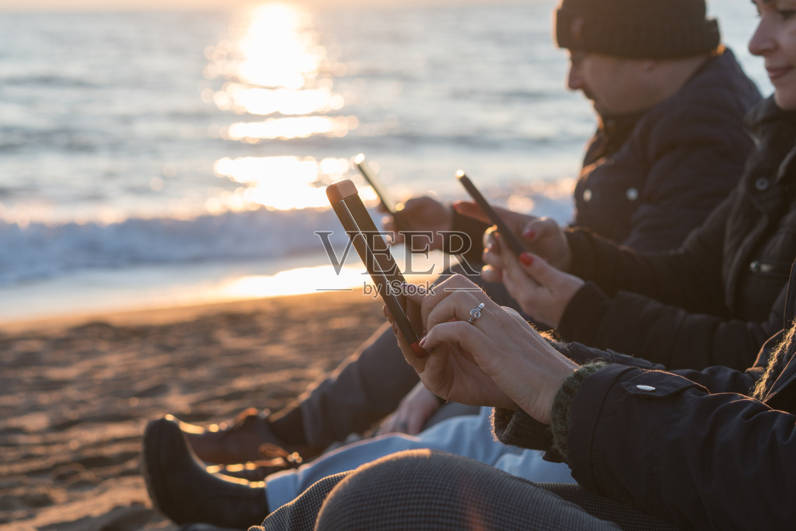 人们在海滩上用手机照片摄影图片