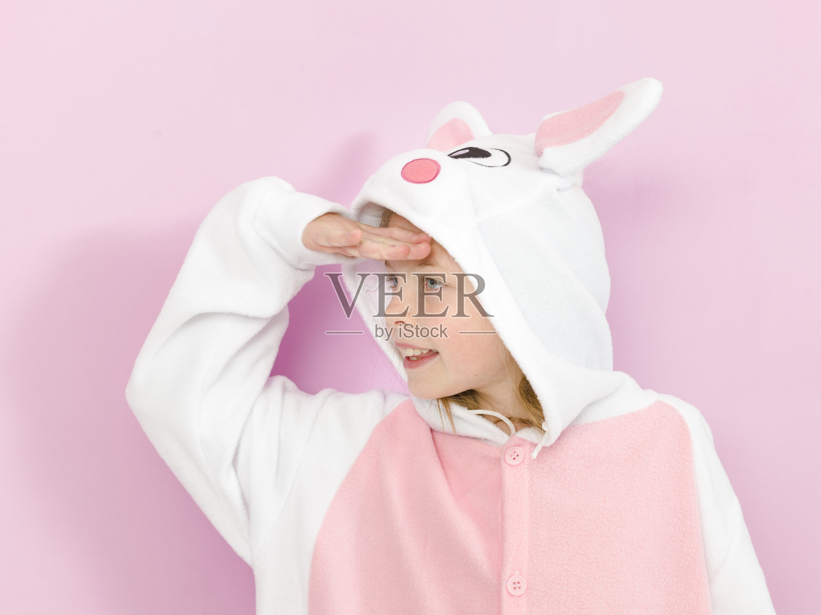 漂亮的金发女孩穿着舒适的兔子服装在工作室粉红色的墙前摆姿势照片摄影图片