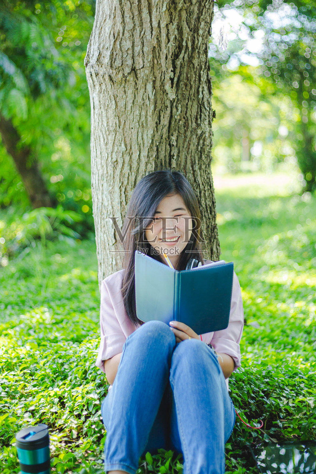 年轻的亚洲女性在公园看书照片摄影图片