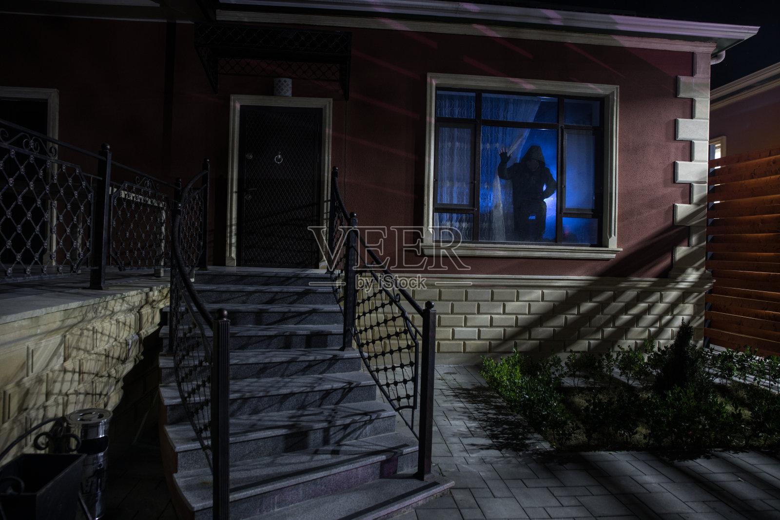 晚上在森林里有一个幽灵的老房子。窗外恐怖的剪影。森林中的旧建筑。超现实的灯。万圣节恐怖的概念照片摄影图片