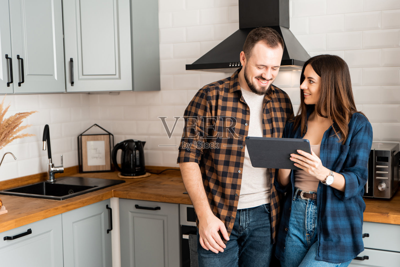 在厨房里拿着平板电脑的女孩和男人照片摄影图片