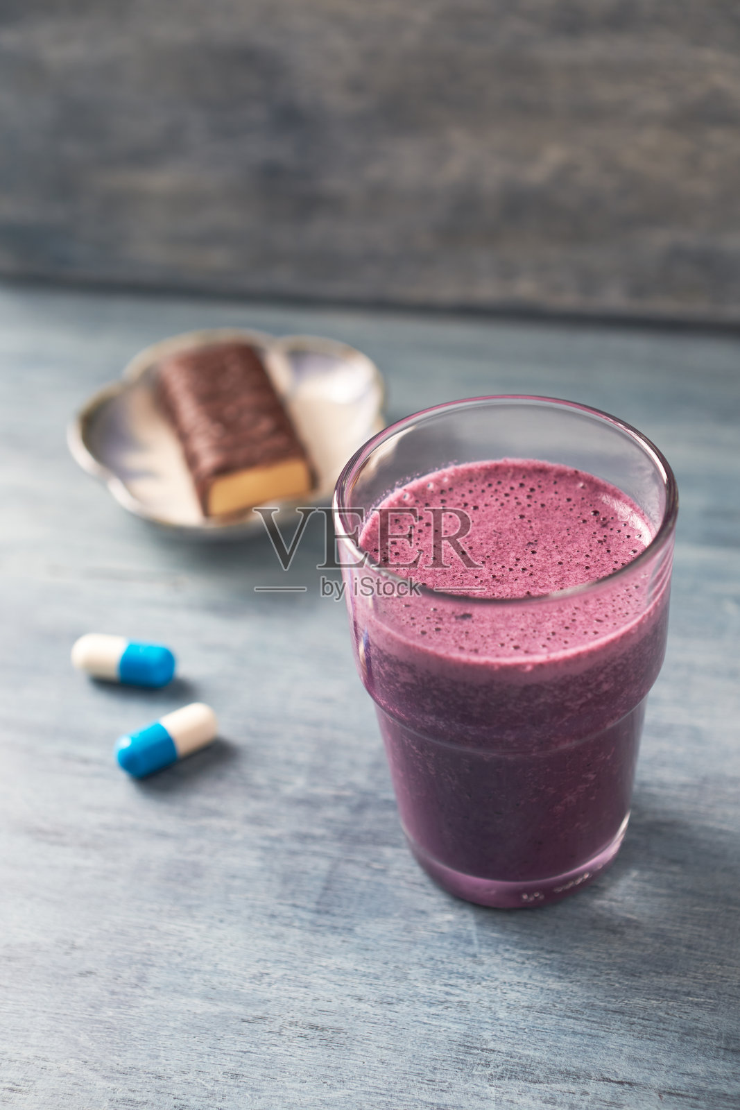 一杯蛋白质奶昔，牛奶和蓝莓，肌酸胶囊和蛋白质棒。运动营养概念。乡村木制背景。副本的空间。照片摄影图片