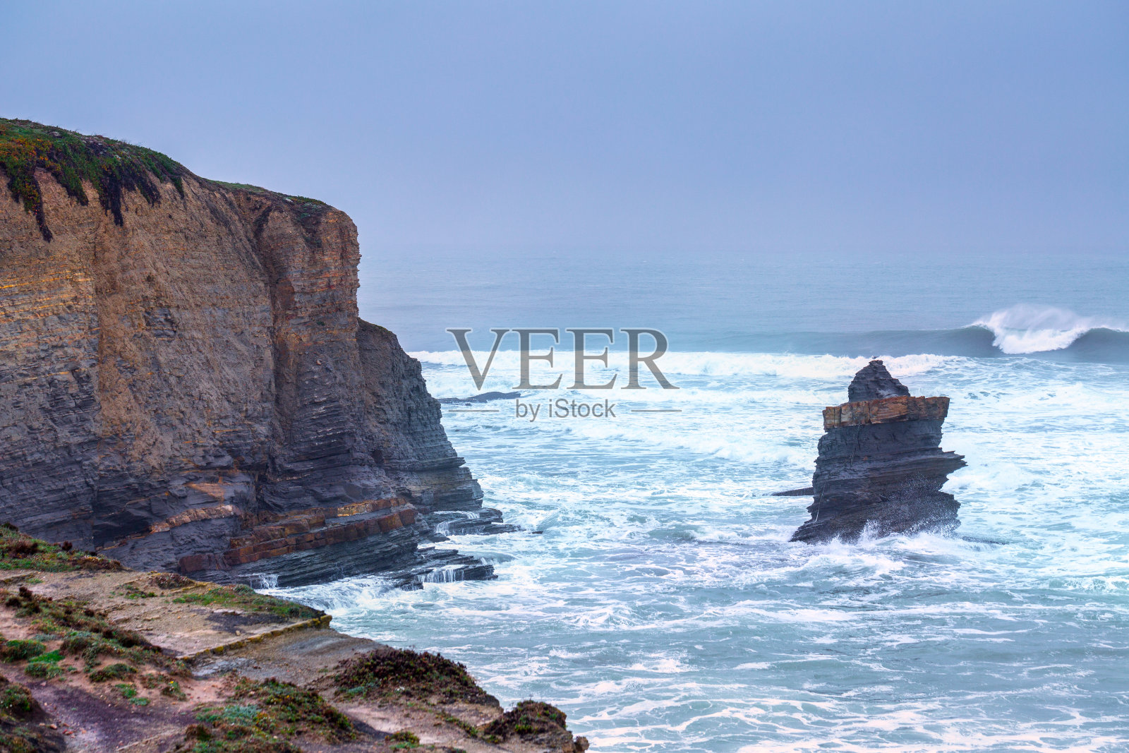 在多云的暴风雨天，巨大的海浪拍打着海岸的悬崖。令人叹为观止的海岸线浪漫海景。Peniche,葡萄牙。照片摄影图片