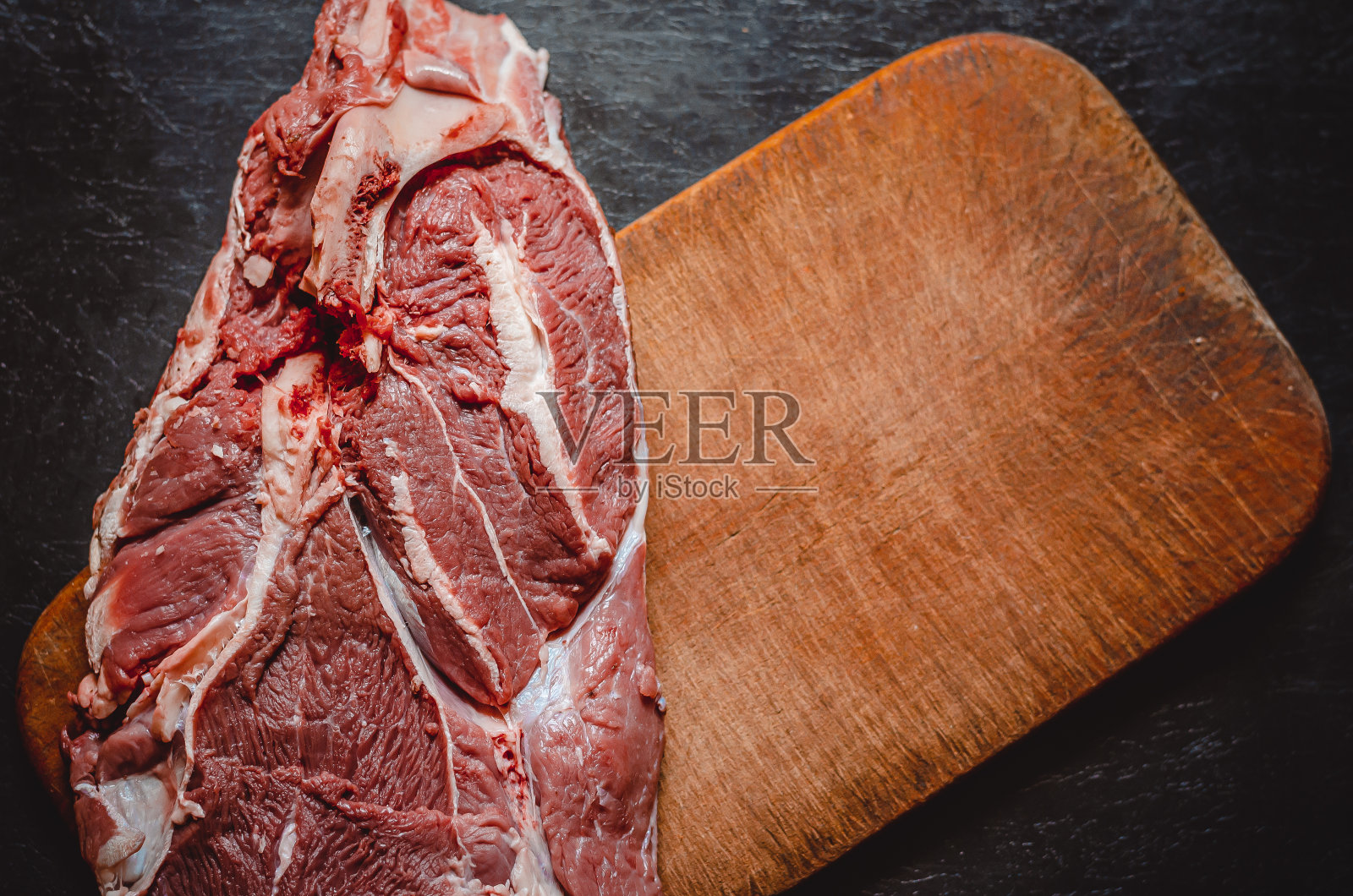 切菜板上的一大块生牛肉。照片摄影图片