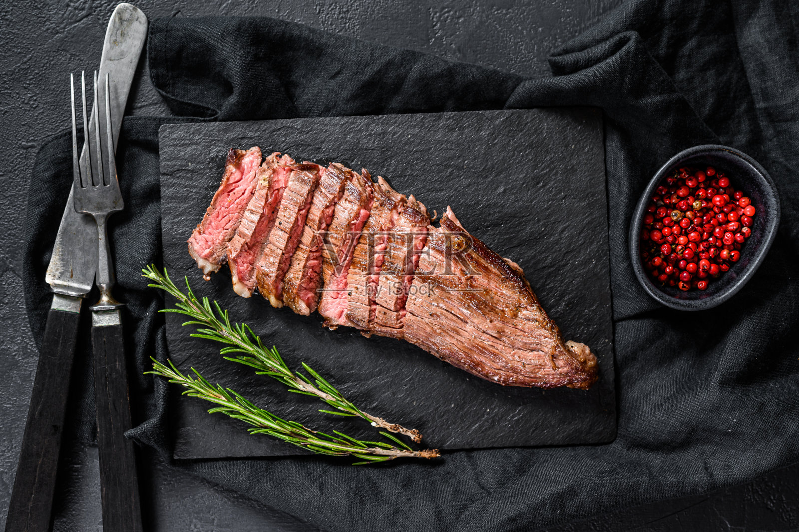 烧烤餐厅牛肉菜单-肋排在一块黑色的石头板上。黑色背景。俯视图照片摄影图片