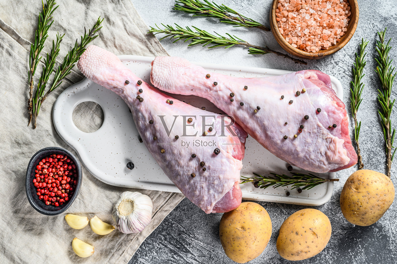白色砧板上带香料的生火鸡腿照片摄影图片