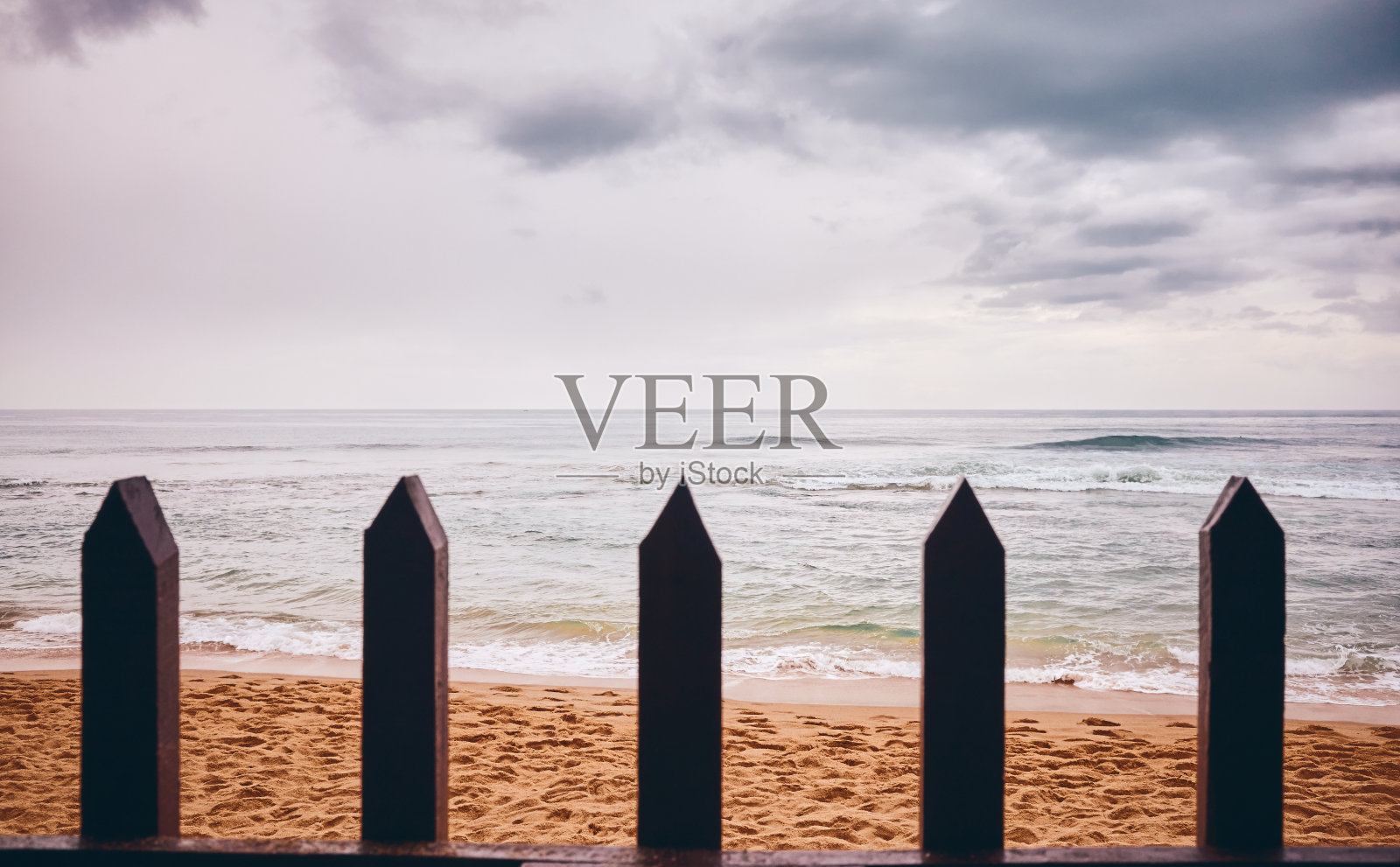 下雨天木栅栏后面的海滩。照片摄影图片