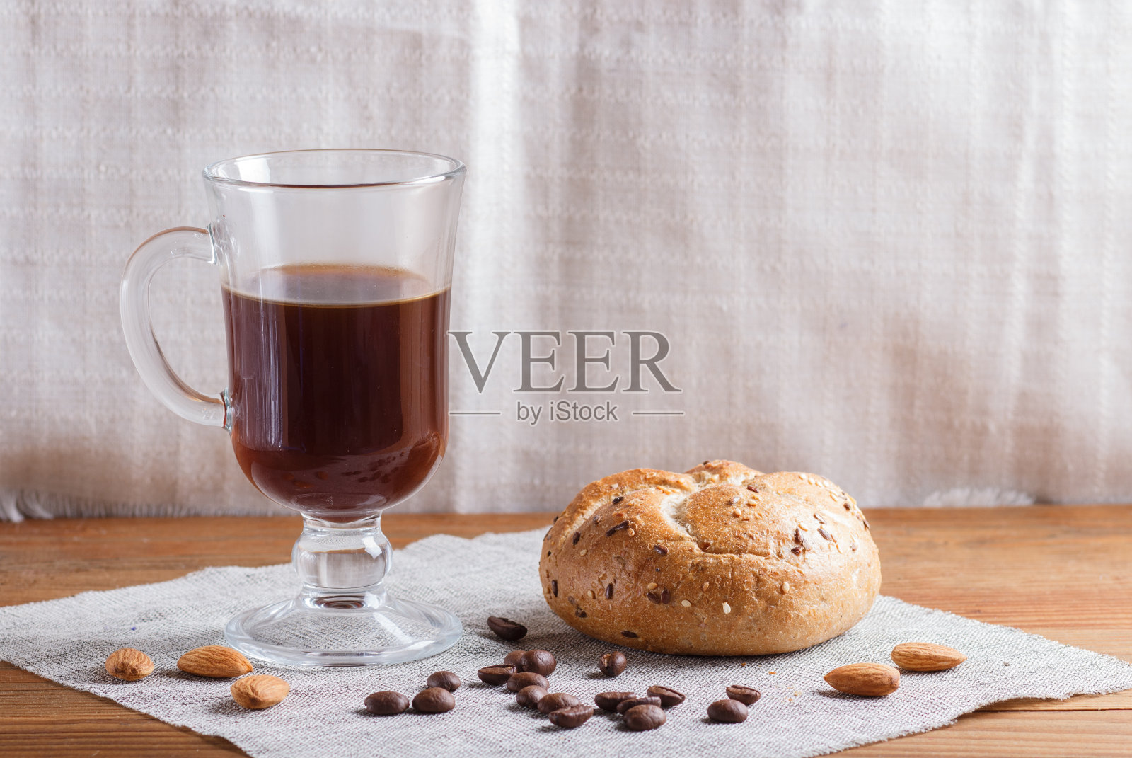 杯子咖啡与面包在一个木制的背景和亚麻纺织品。关闭，复制空间。照片摄影图片