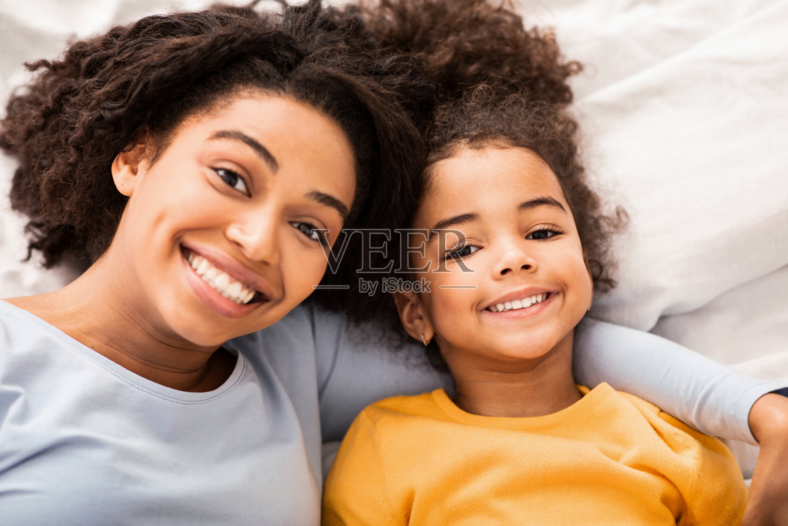 非洲裔母亲和女儿躺在卧室的床上，俯视图照片摄影图片