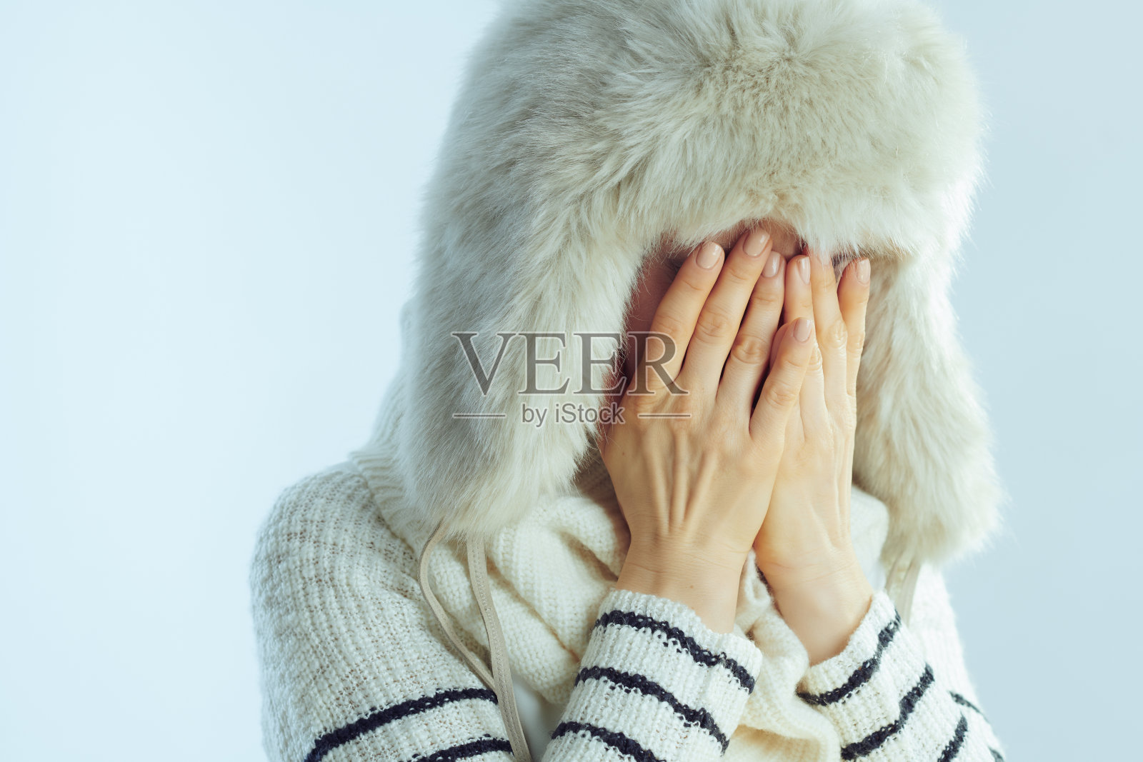 悲伤的女人孤独的哭泣在冬天浅蓝色的背景照片摄影图片