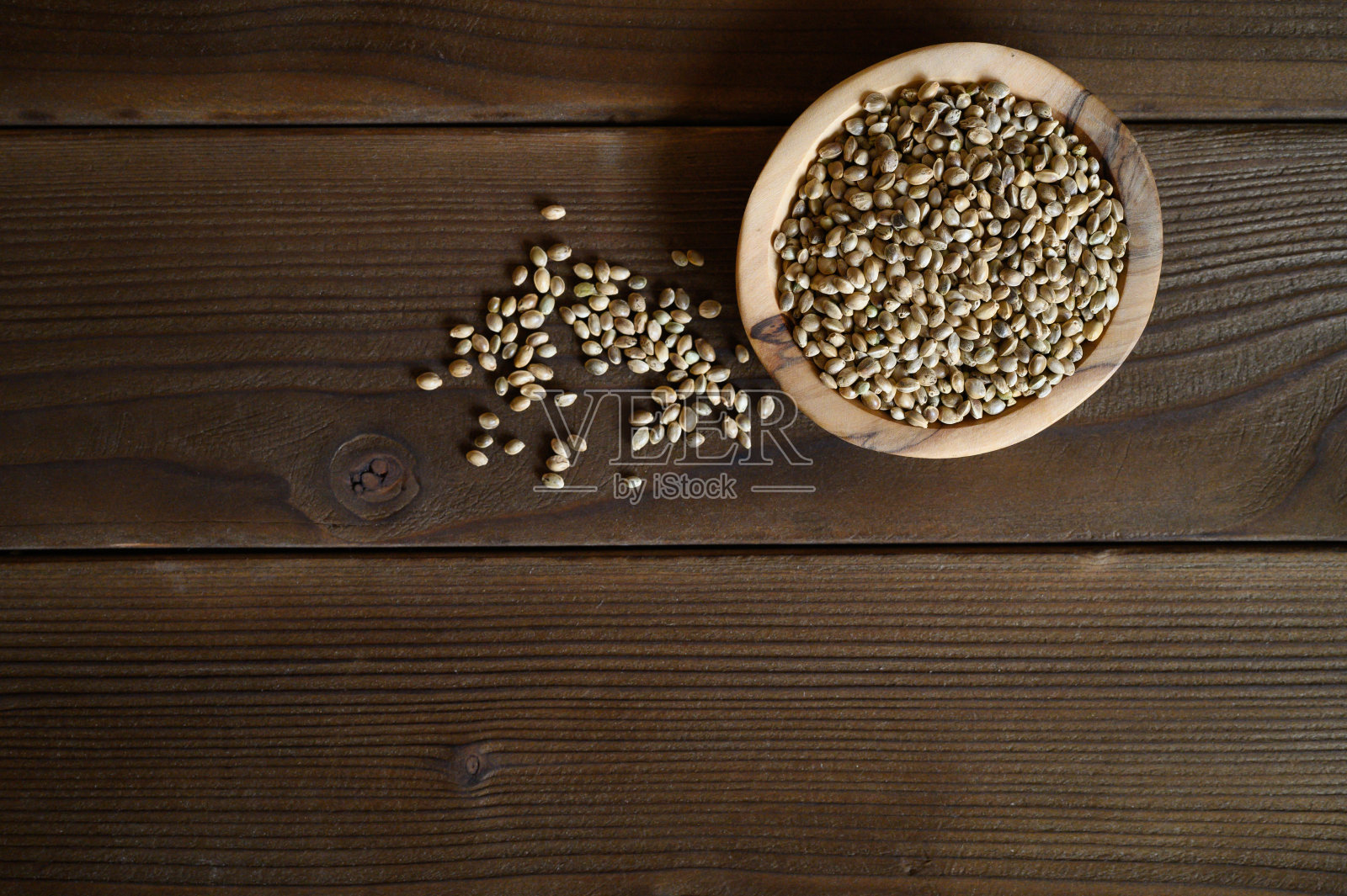 大麻种子在一个木制的乡村碗在一个深色的木制背景。平躺，文字空间照片摄影图片