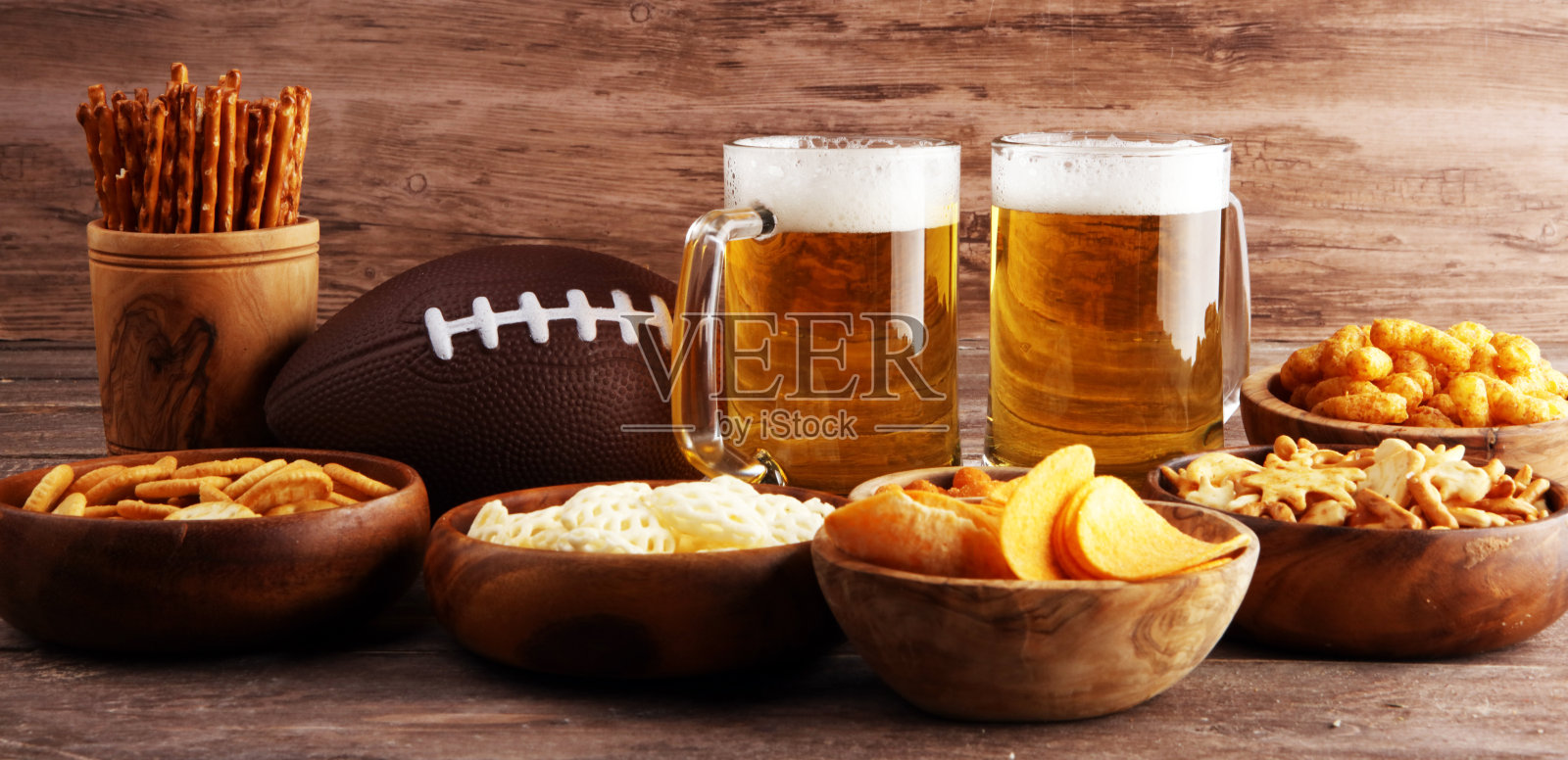 桌上放着薯条、咸味小吃、足球和啤酒。非常适合碗游戏零食项目。照片摄影图片