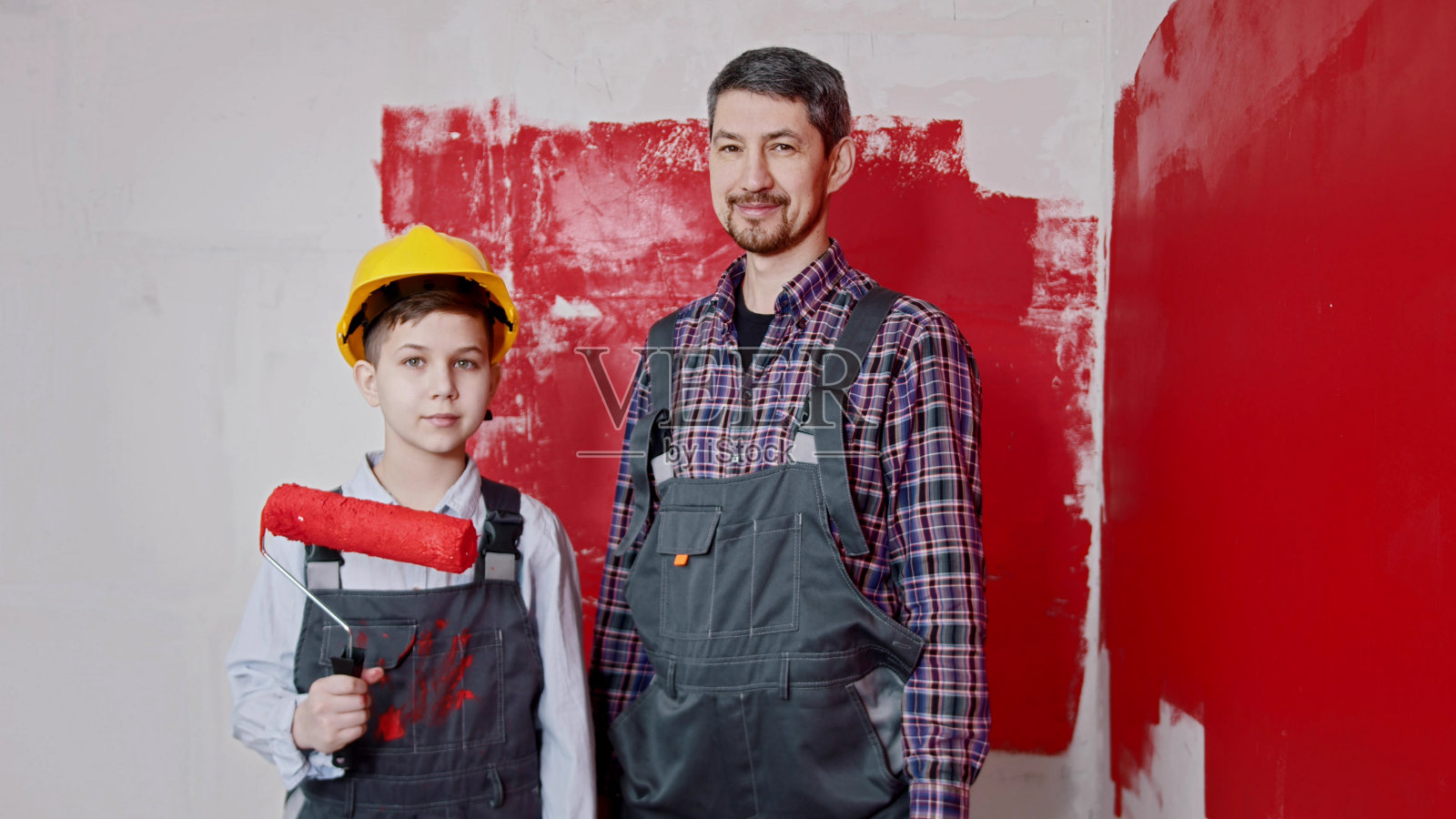 小男孩和他的父亲站在房间里拿着墙面涂料滚筒照片摄影图片