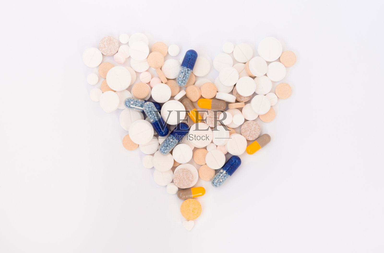 一堆五颜六色的心形药丸，药片和胶囊在白色的背景。药物处方为治疗用药保健理念，俯视图有拷贝空间照片摄影图片