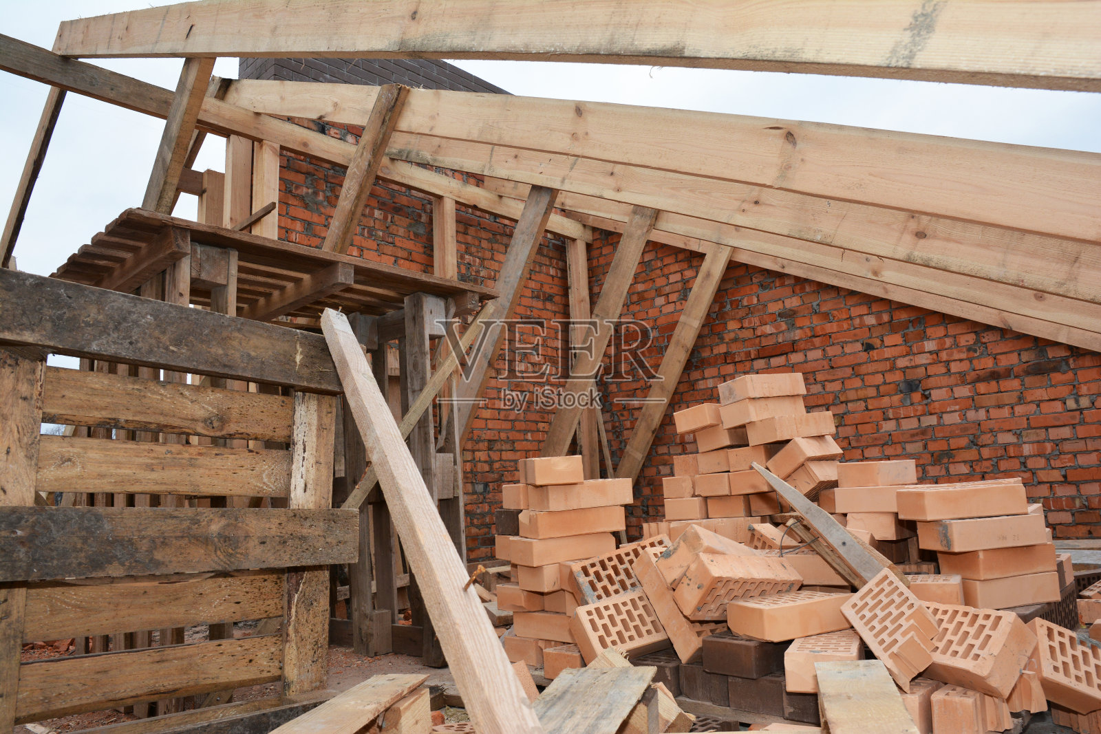 未完工的房屋屋顶屋顶结构有阁楼桁架、木梁、屋檐、木材和砖垛照片摄影图片