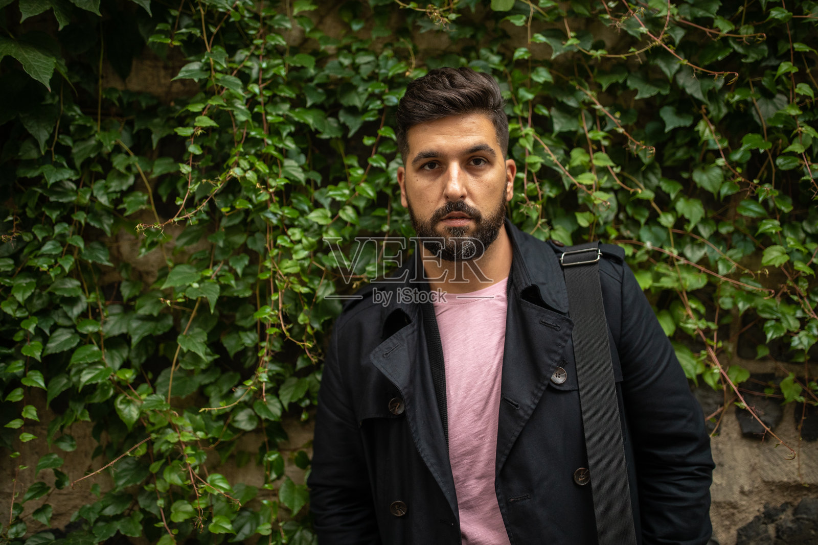 商人站在爬山虎的墙前照片摄影图片