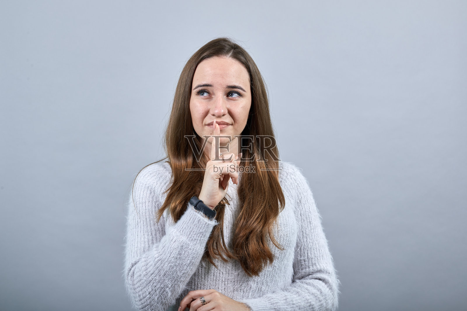 迷人女子手指放在嘴边，微笑示意安静照片摄影图片