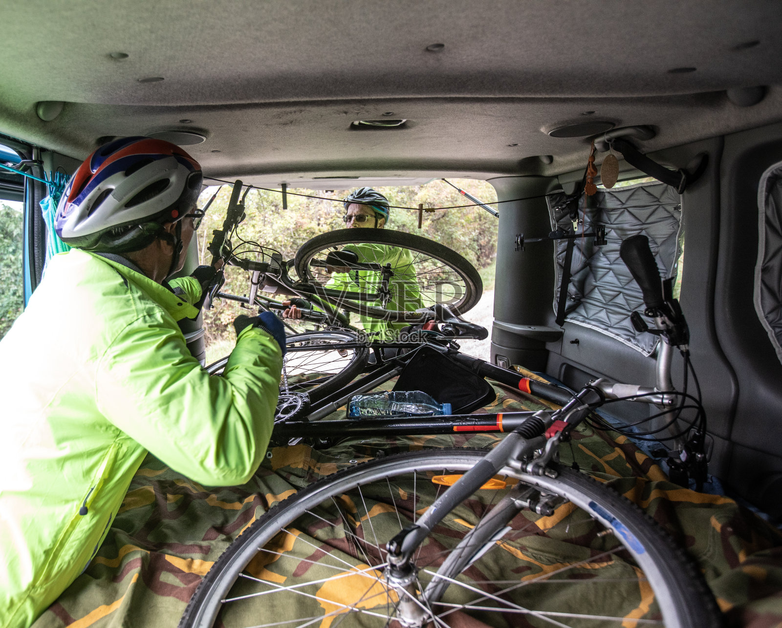 两个朋友互相帮助，把自行车放在汽车库存的照片里照片摄影图片