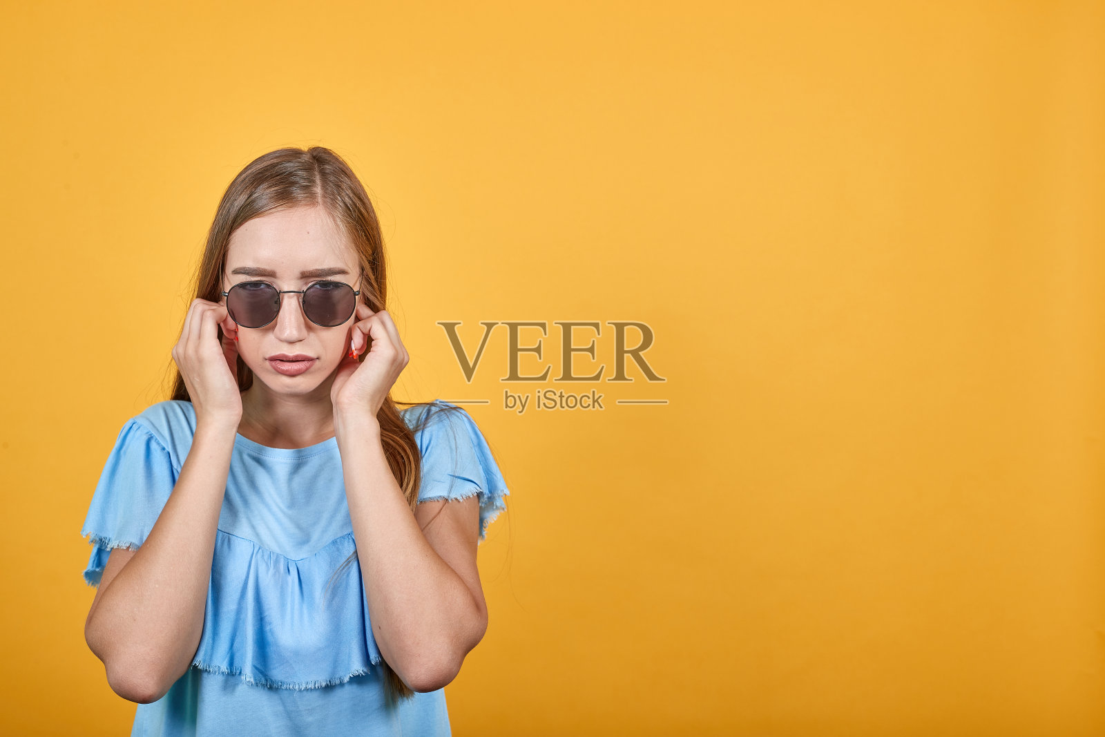 在橙色背景下的穿蓝色T恤的棕发女孩照片摄影图片