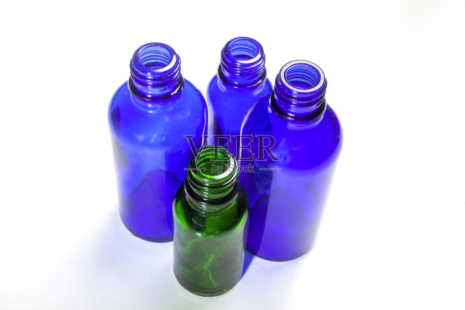 四个瓶子，一个绿色的，三个蓝色的照片摄影图片