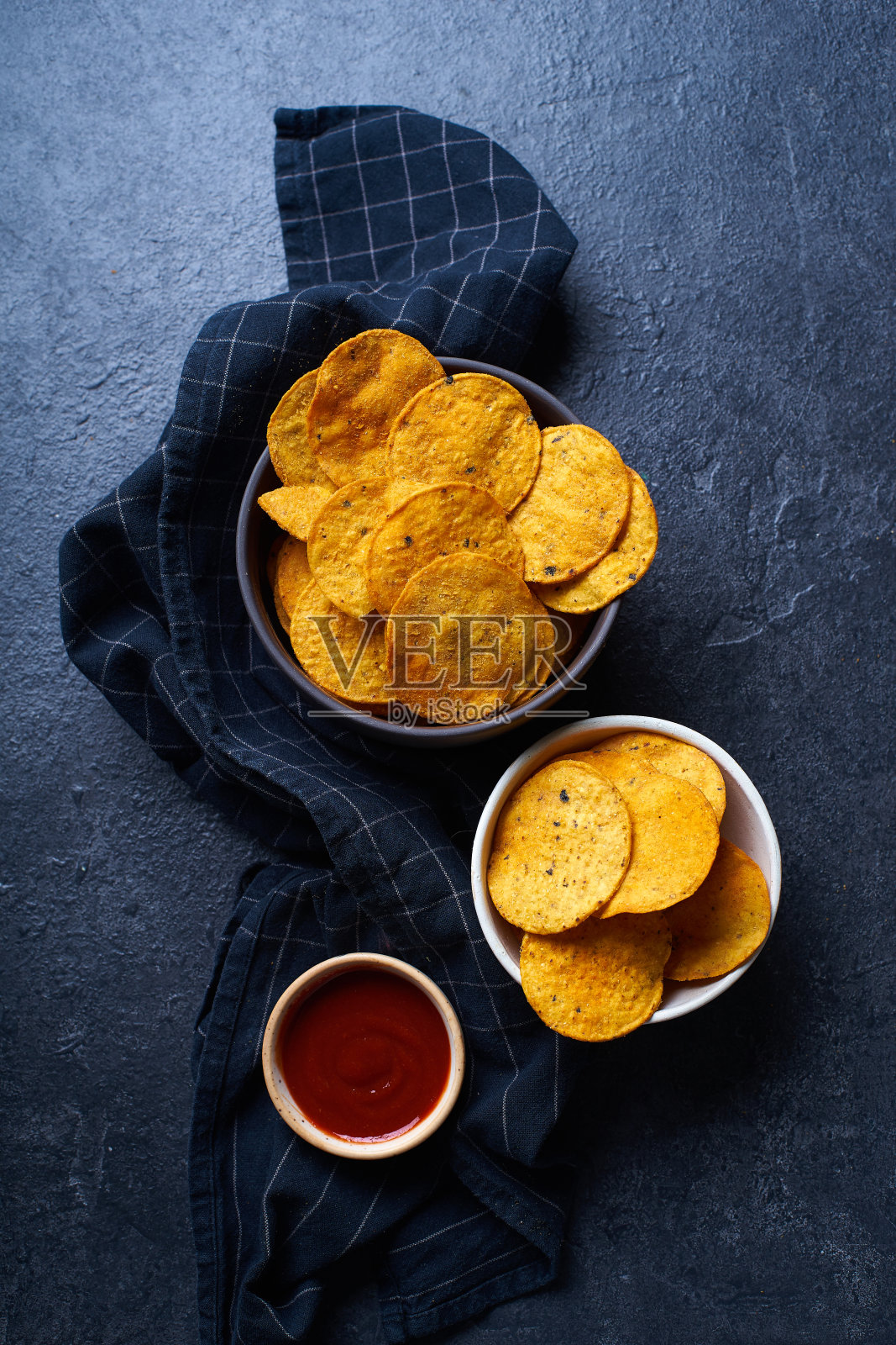 墨西哥圆形玉米片和辣辣酱放在两个碗里。俯视图芯片上的黑暗背景与复制空间照片摄影图片