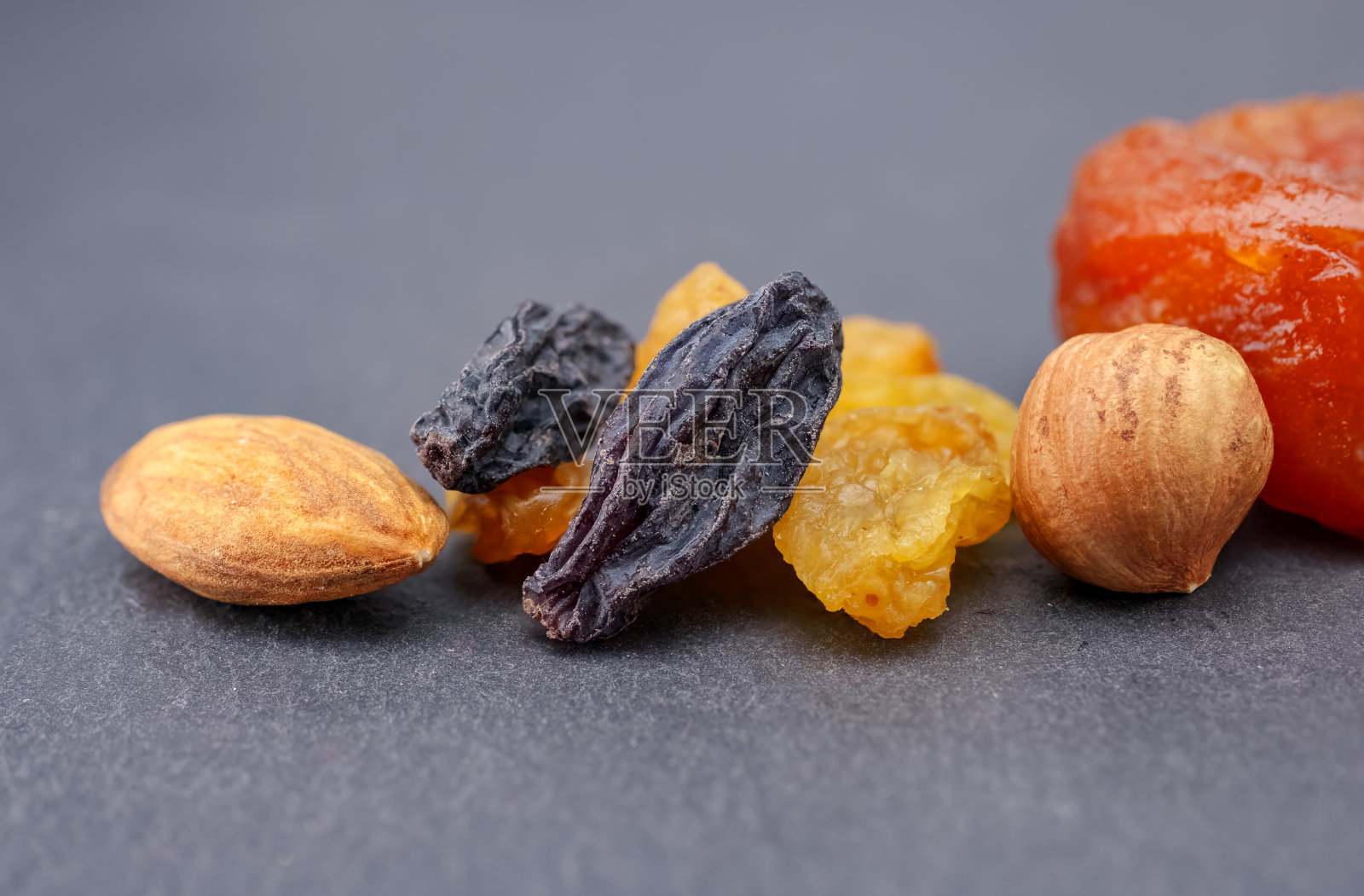 健康食品。干果:坚果，葡萄干，腰果，杏干，榛子，杏仁，灰色背景。照片摄影图片