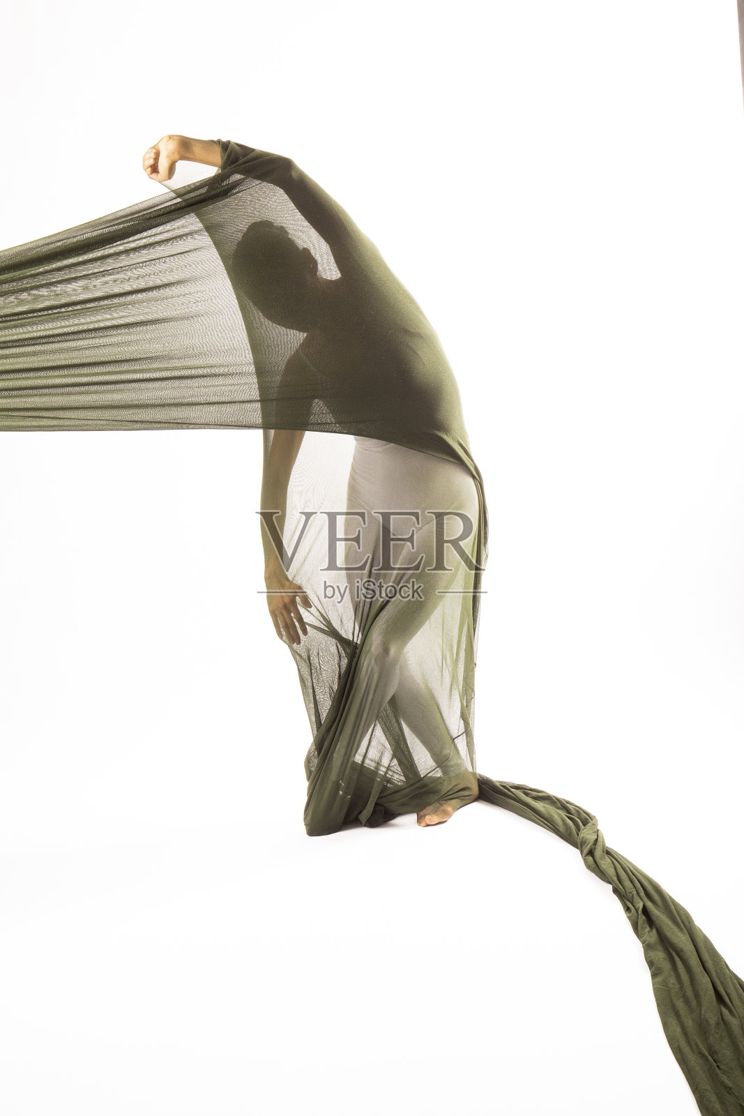 在演播室里，一个成年女子在一根布料管里跳舞。照片摄影图片