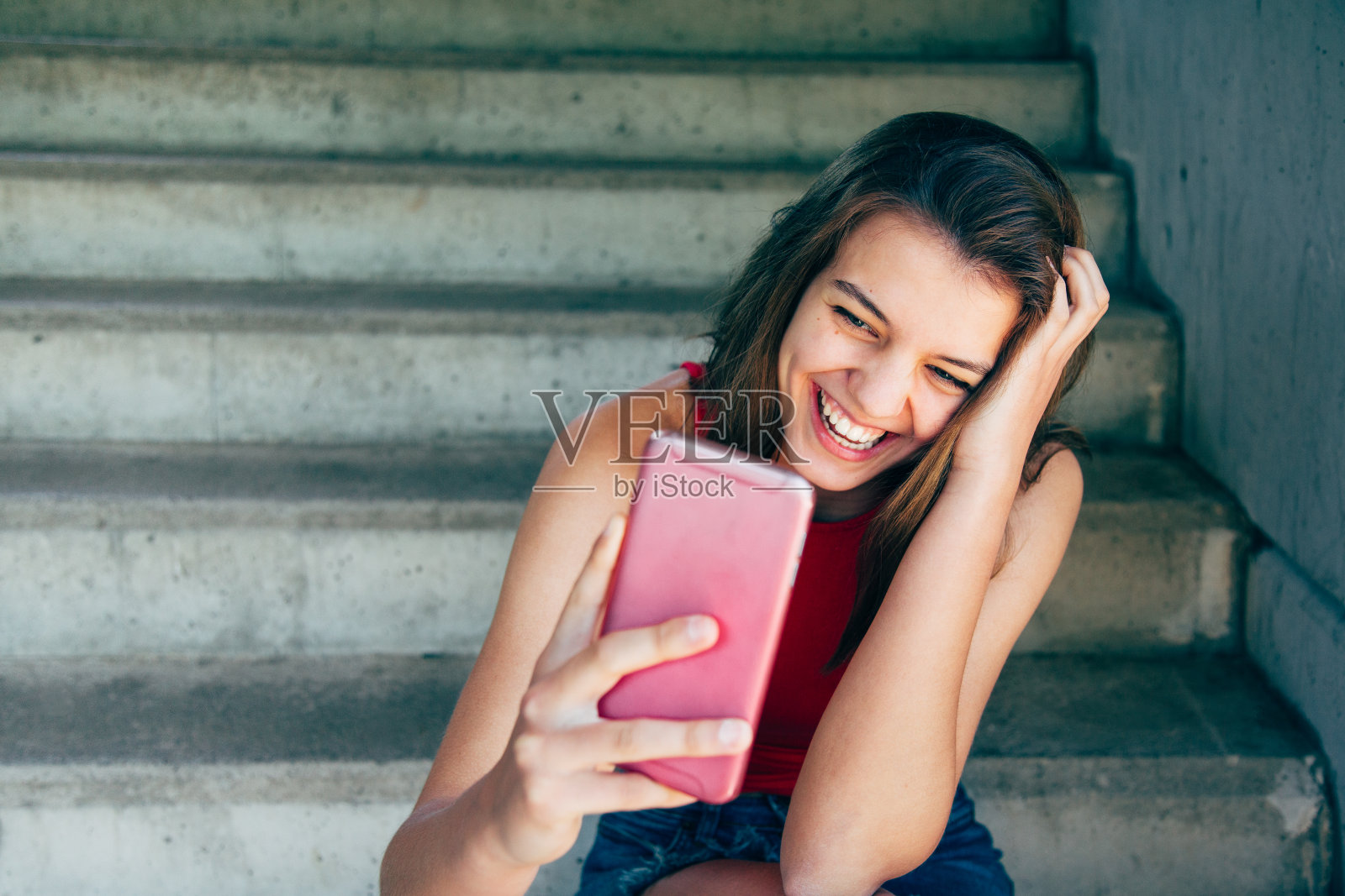 少女在使用智能手机时大笑照片摄影图片