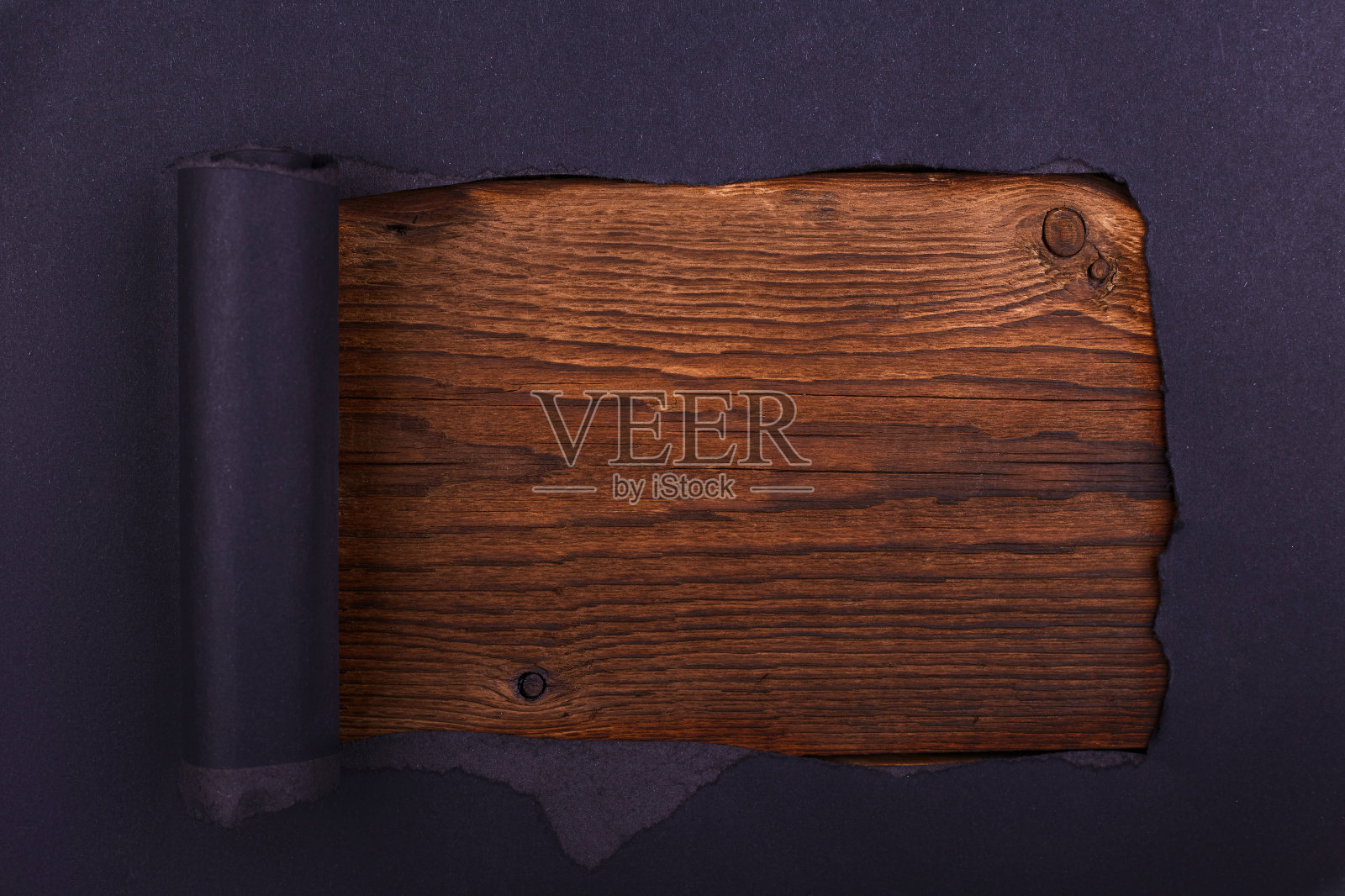 黑纸上有个大洞。撕裂。木制背景。抽象的背景。照片摄影图片