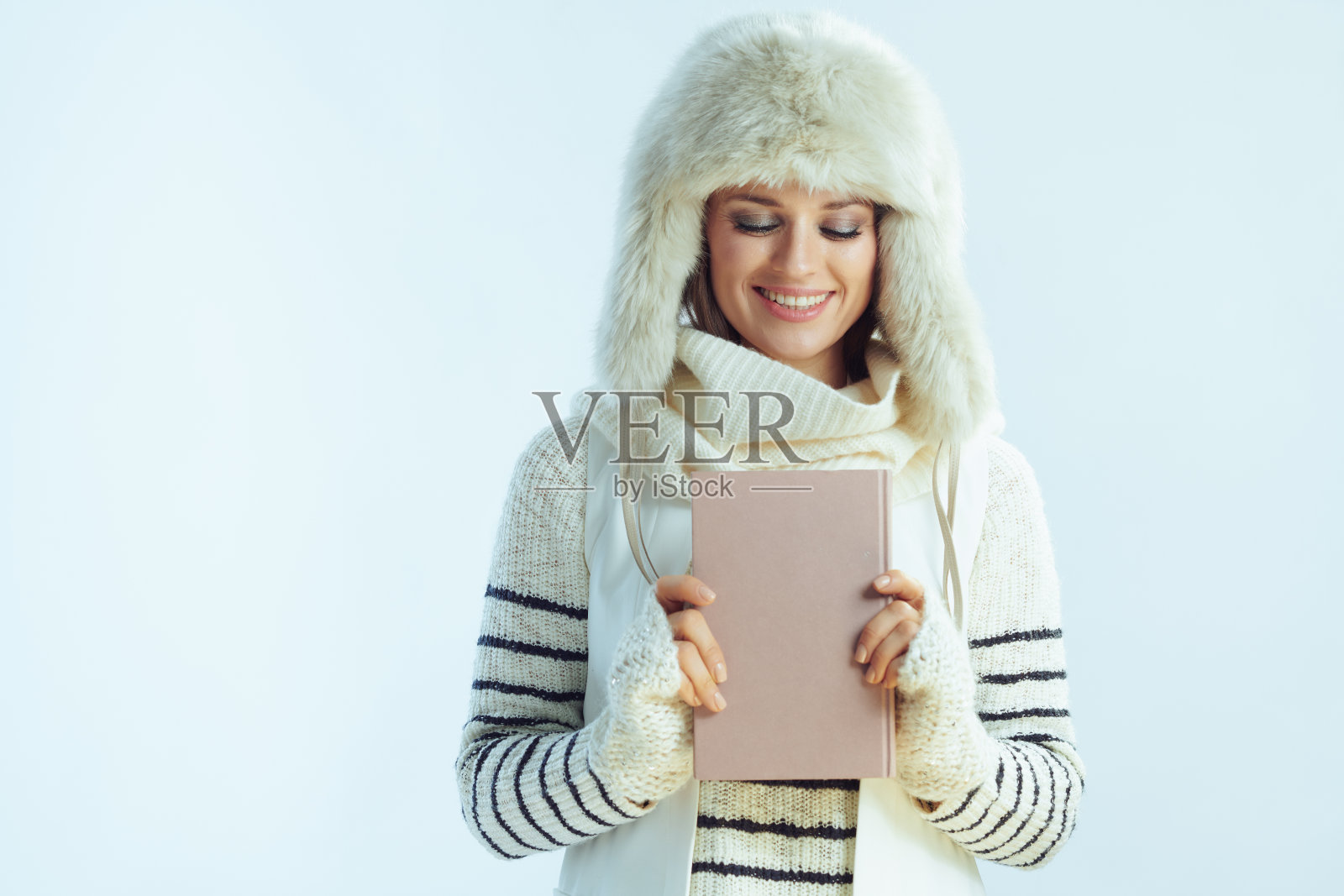 在冬季浅蓝色背景下看书的女人照片摄影图片