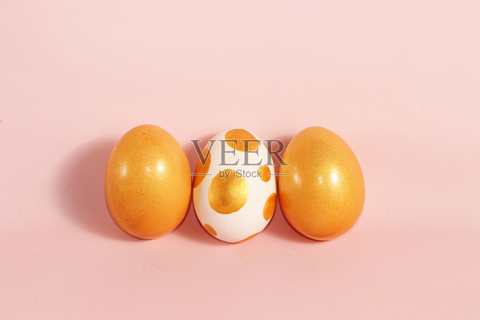 粉红色背景上装饰的金色复活节彩蛋。最小的节日的概念。复活节快乐背景。在家创造性的画鸡蛋，简单的想法画上色照片摄影图片