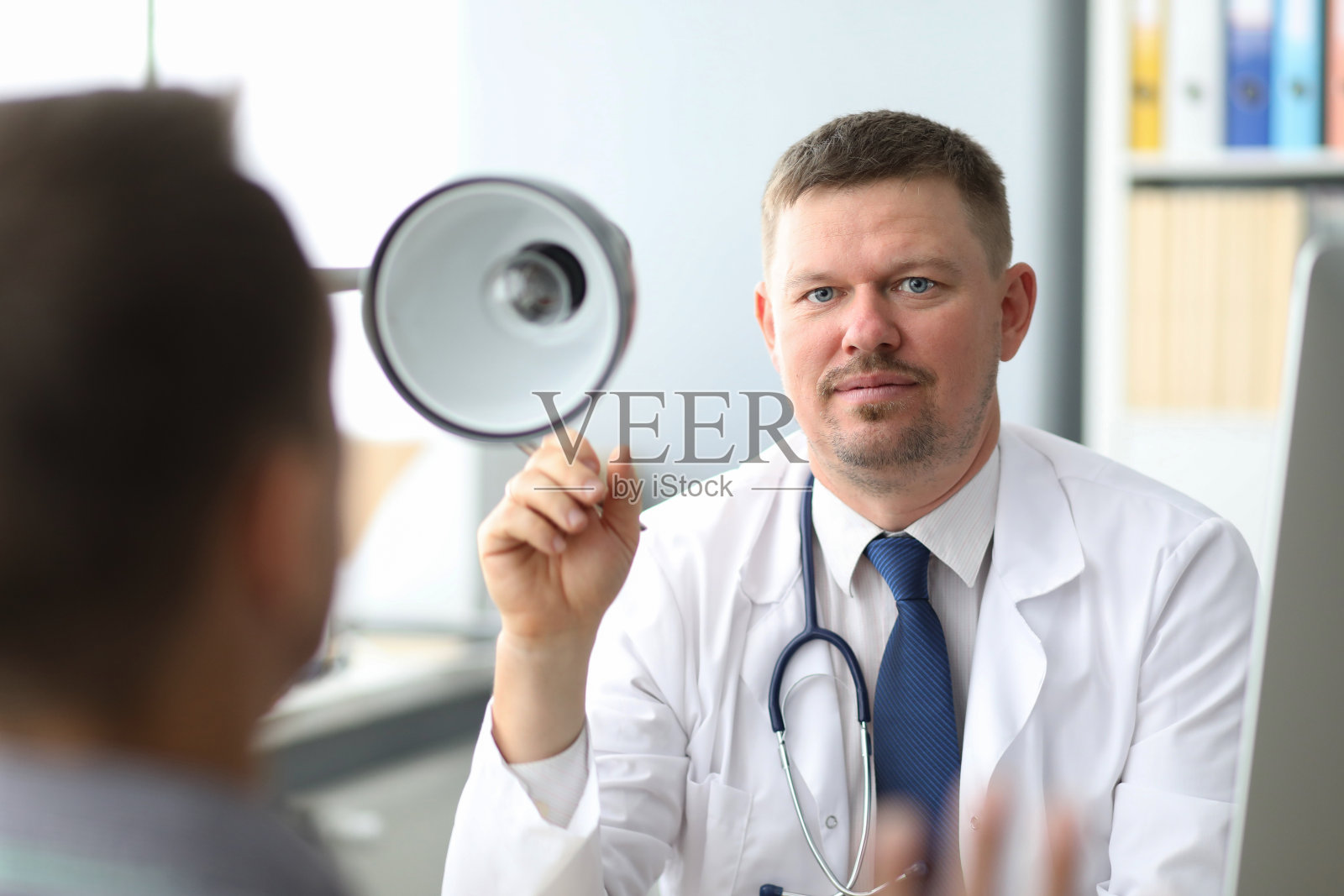 医生倾听病人讲述病情，男医生做笔记，拍摄桌子上的手部照片摄影图片