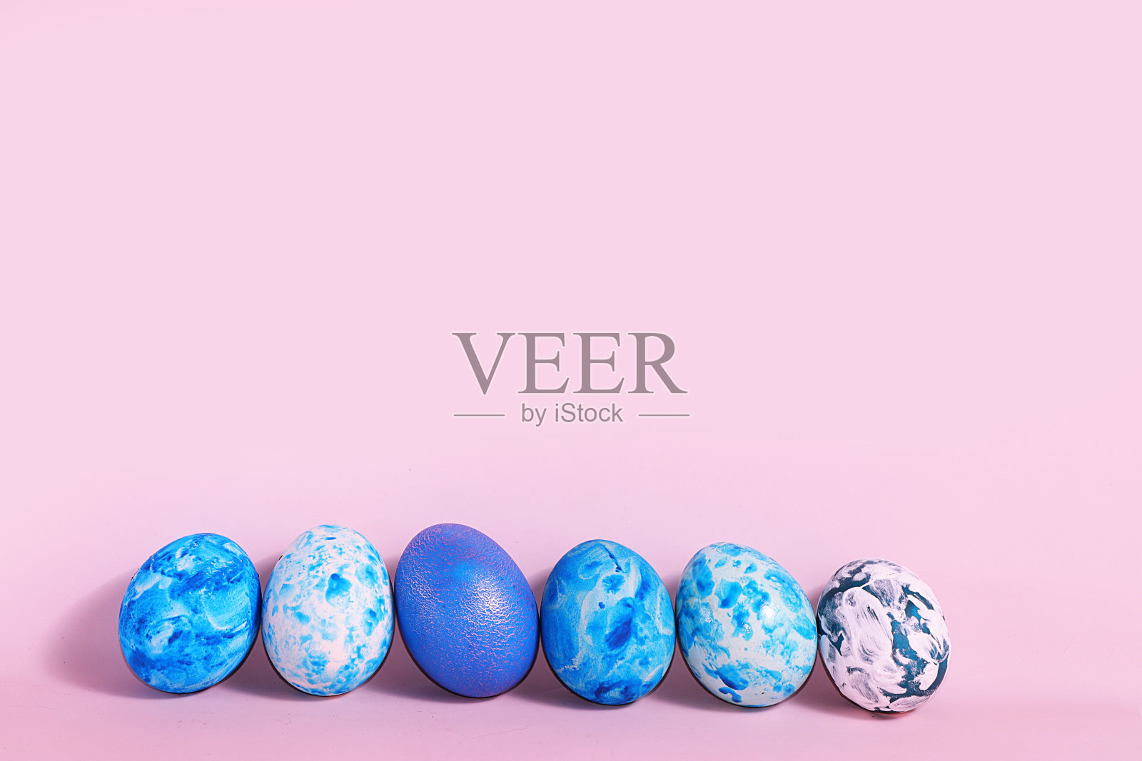 粉红色背景上装饰的蓝色复活节彩蛋。最小的节日的概念。复活节快乐背景。在家创造性的画鸡蛋，简单的想法画上色照片摄影图片