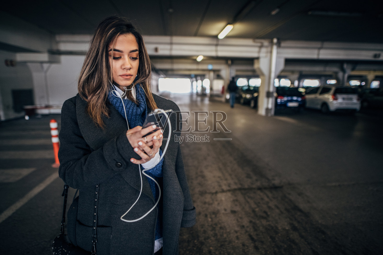 一个女人在地下车库用智能手机听音乐照片摄影图片