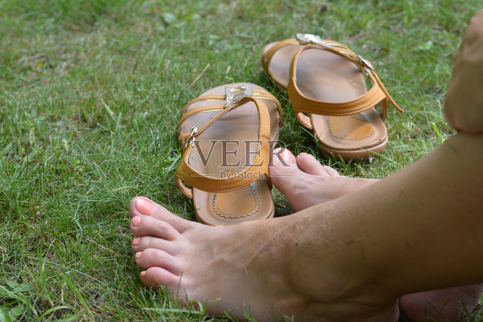女性的脚赤脚躺在绿色的草地上，夏天穿着鞋子照片摄影图片