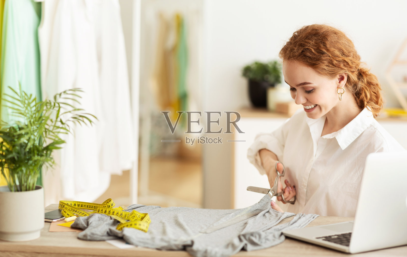 成功的裁缝在自己的工作室里裁剪灰色面料照片摄影图片