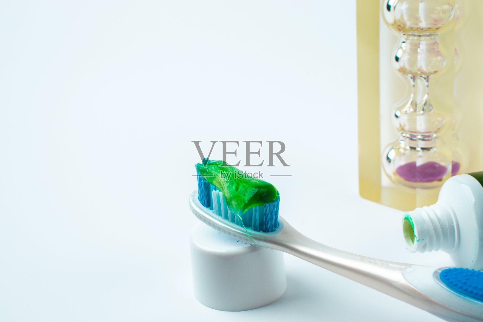 牙刷与绿色凝胶牙膏隔离白色背景与沙漏照片摄影图片